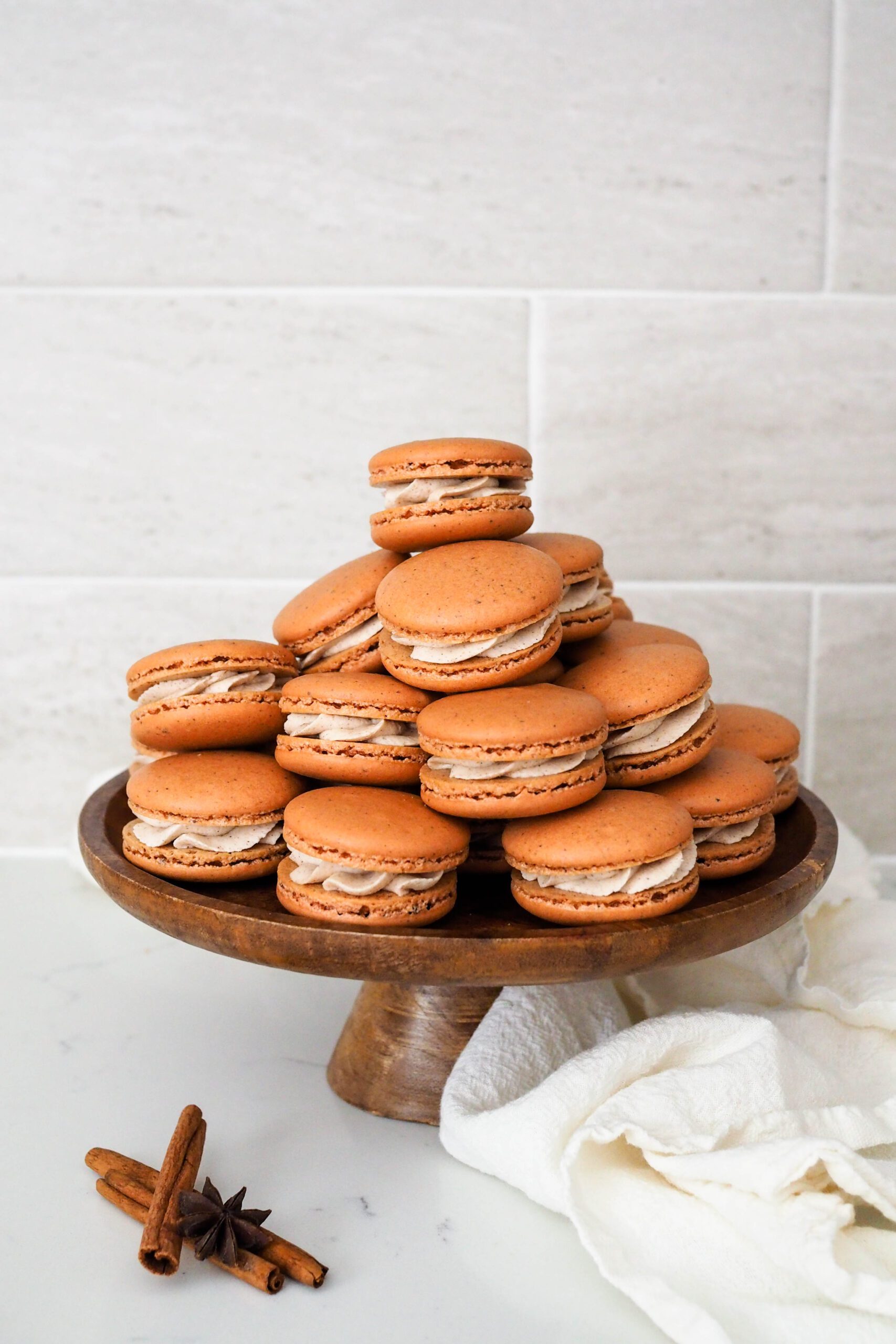 A cake platter is piled with chai macarons.