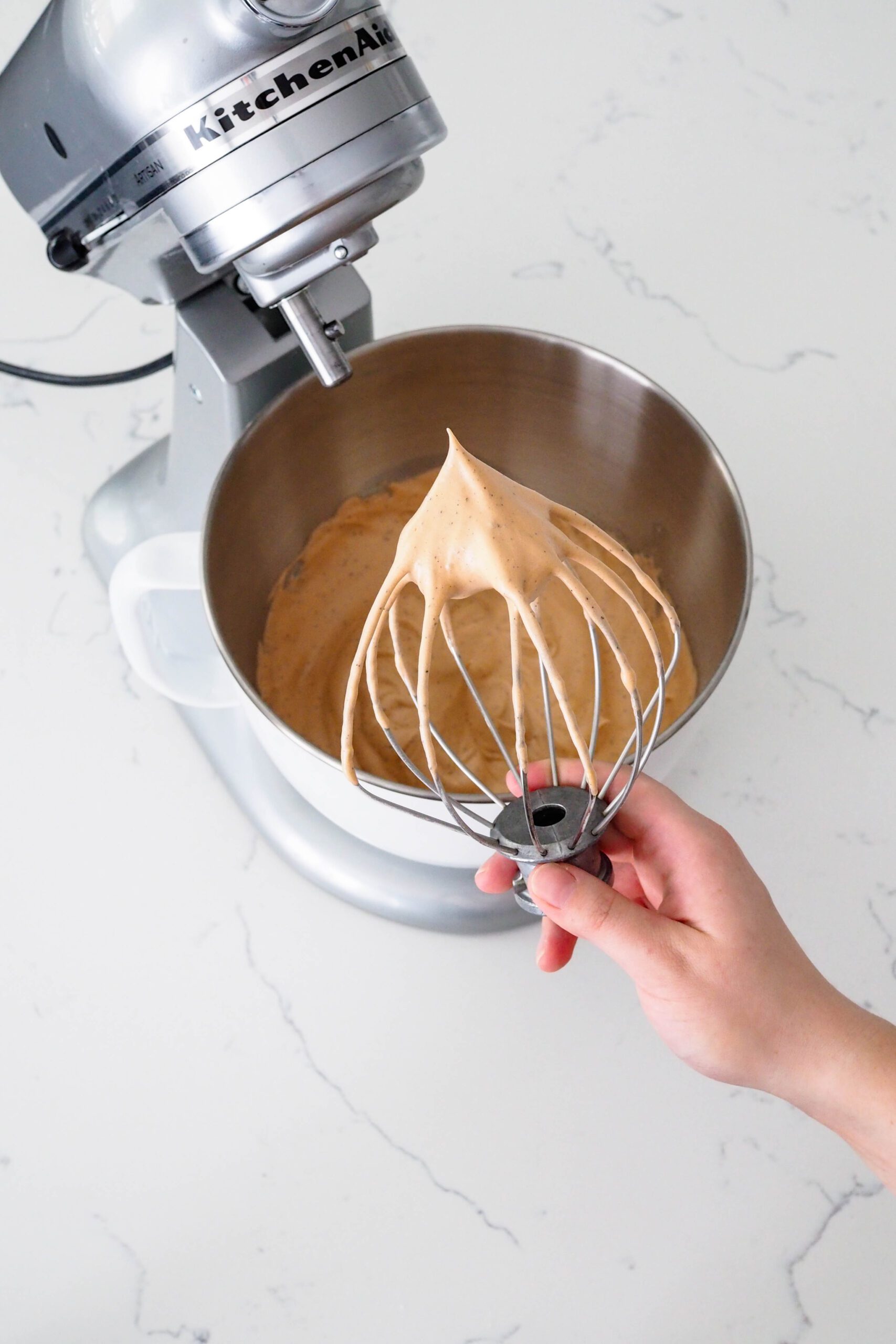 A whisk with thick clumps of stiff-peaked meringue.