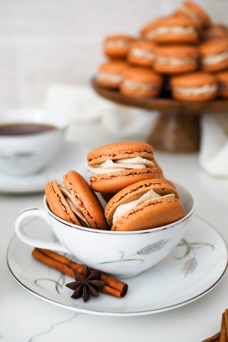 Chai macarons are piled in a tea cup.