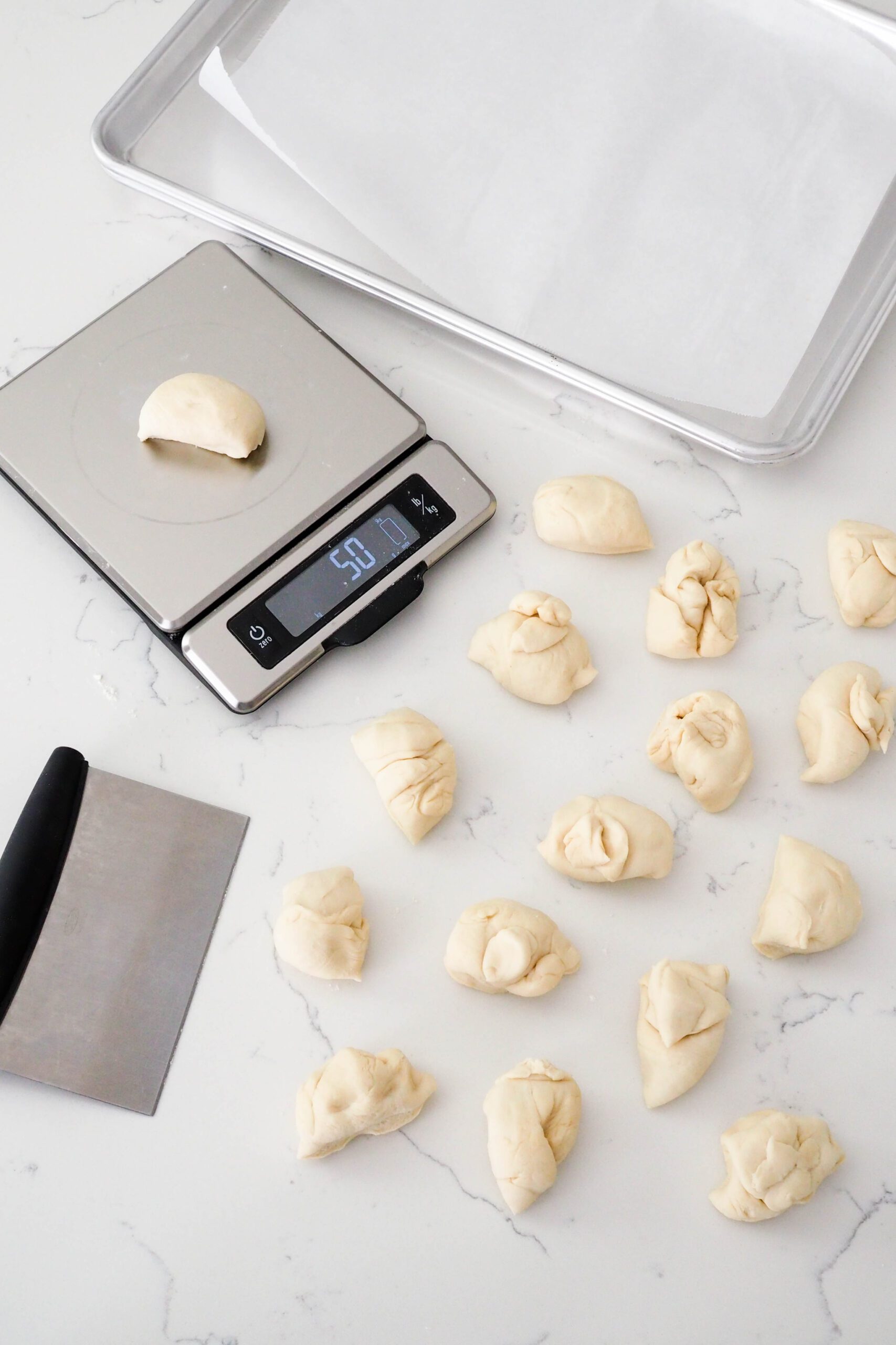 16 pieces of enriched dough are divided on a counter.