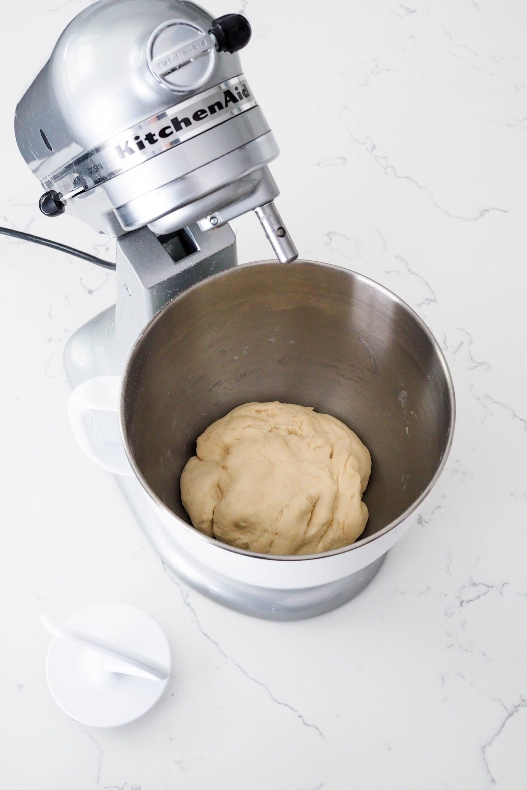 Freshly kneaded enriched dough in a mixer bowl.