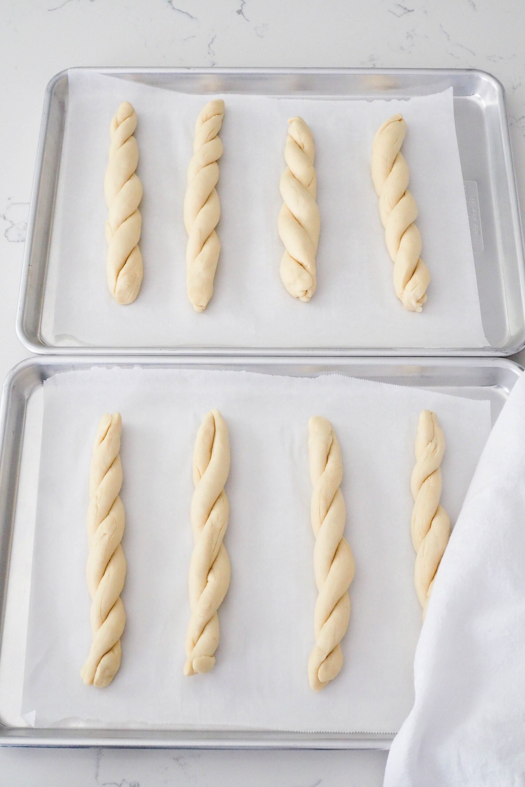 Eight twisted garlic breadsticks on a baking sheet.