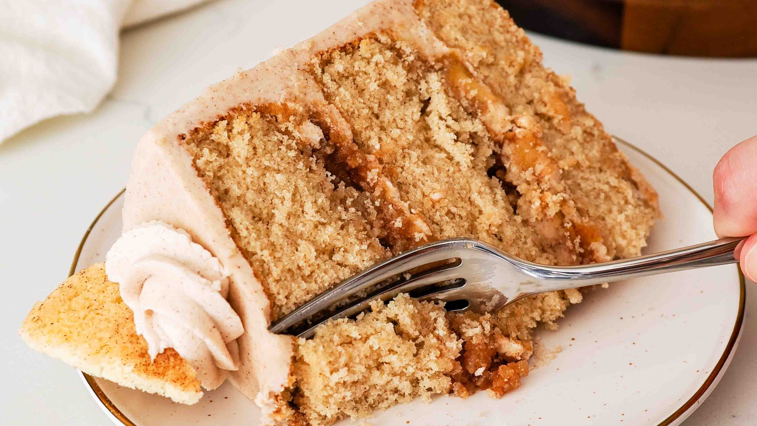 A fork takes a piece out of a slice of apple snickerdoodle layer cake.