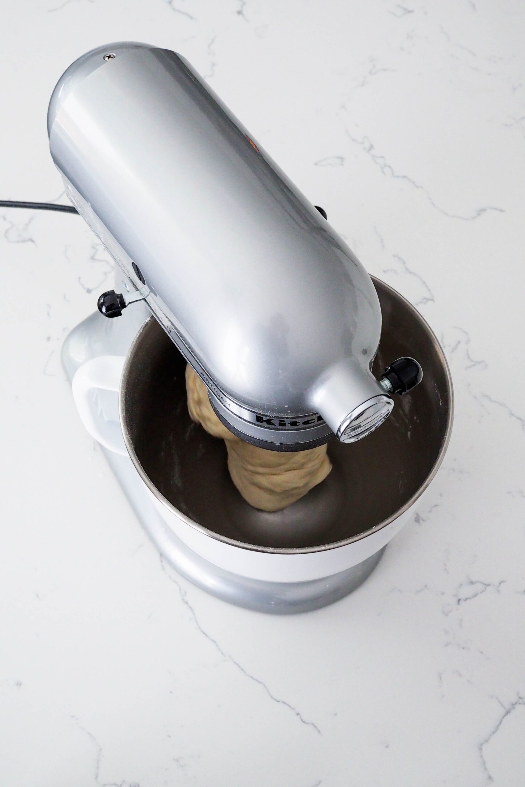 Enriched dough is kneaded in a stand mixer. The sides of the bowl are clean.