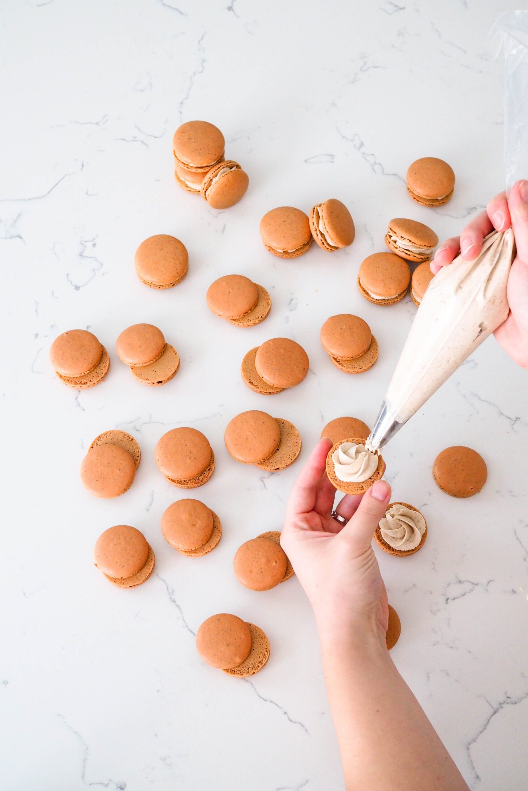 A swirl of chai buttercream is piped onto a macaron shell.