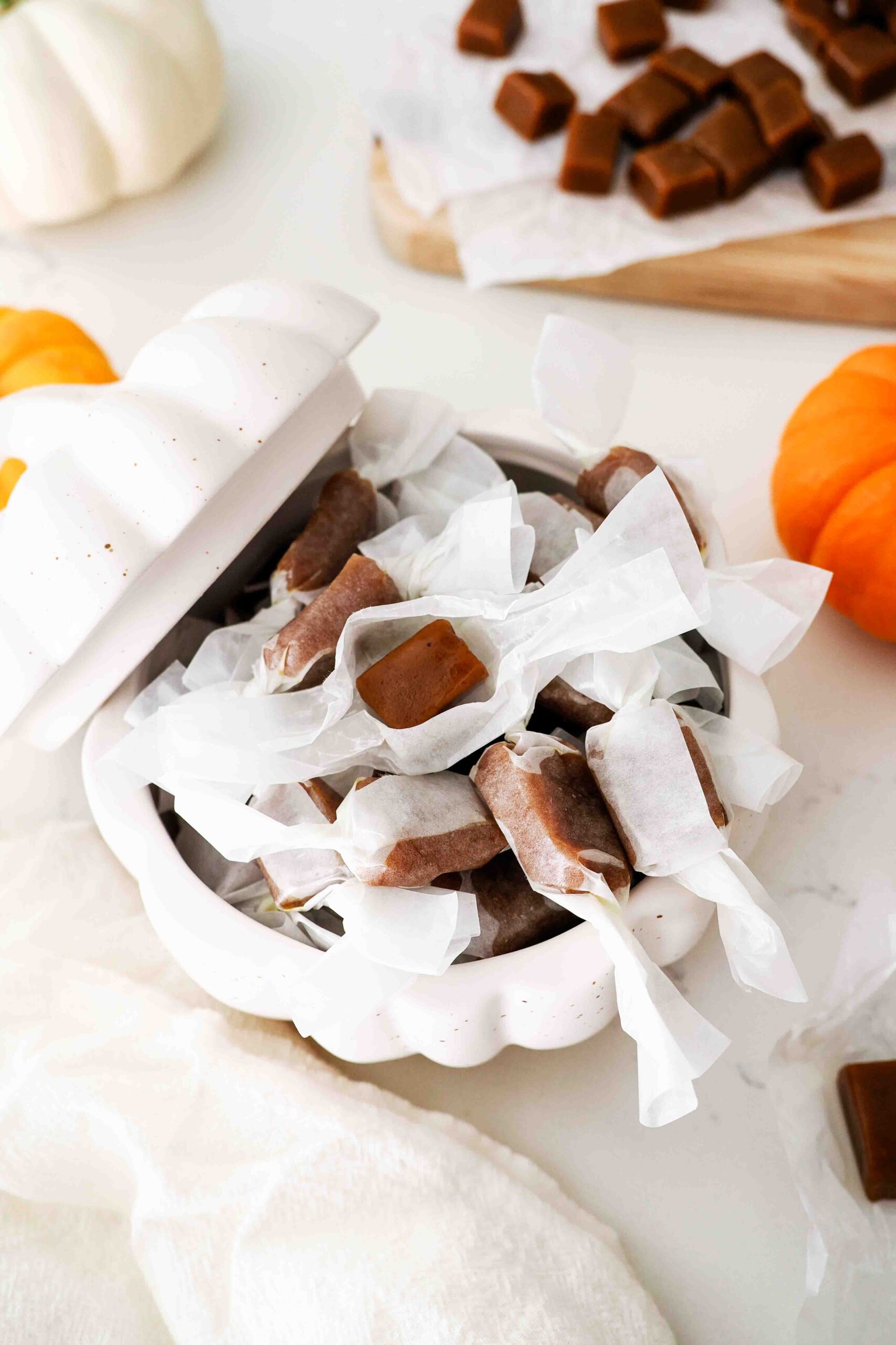 A stoneware pumpkin is filled with wrapped pumpkin spice caramels.