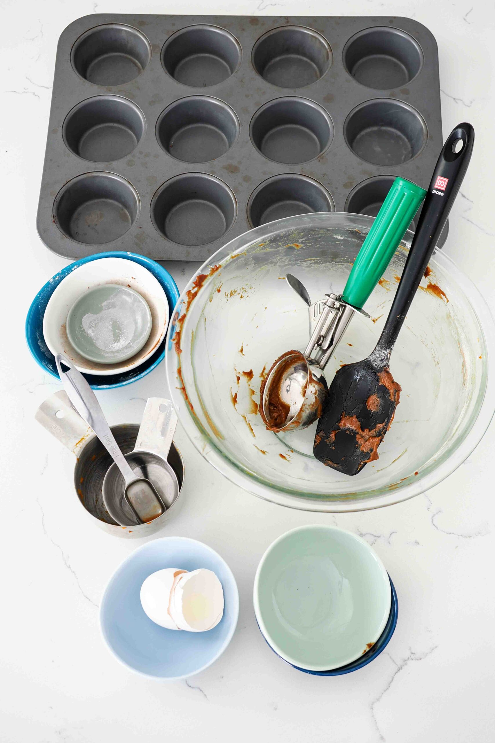 All the dishes used to make chocolate pumpkin muffins on a quartz counter.