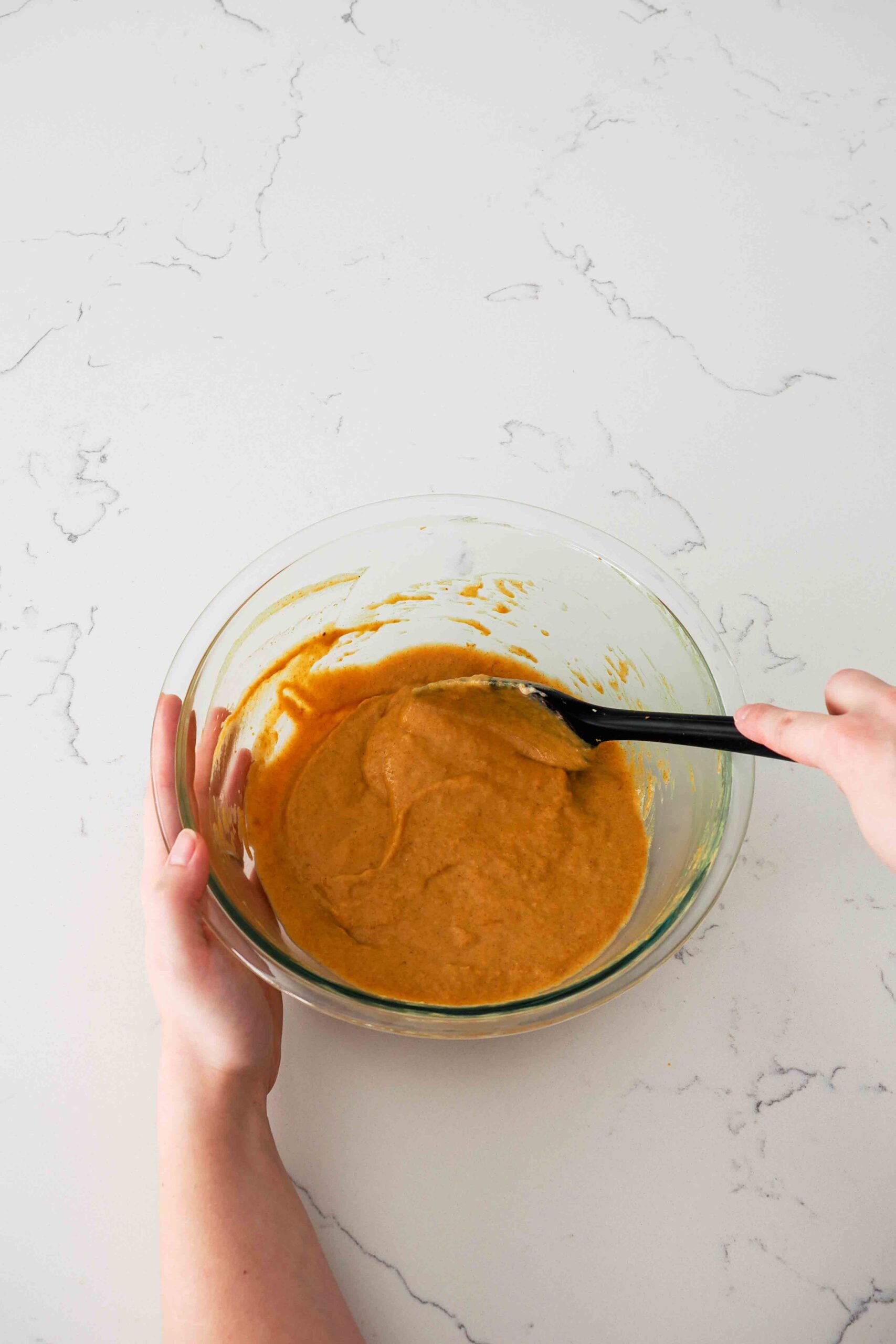 Pumpkin pie filling being stirred together in a glass bowl.