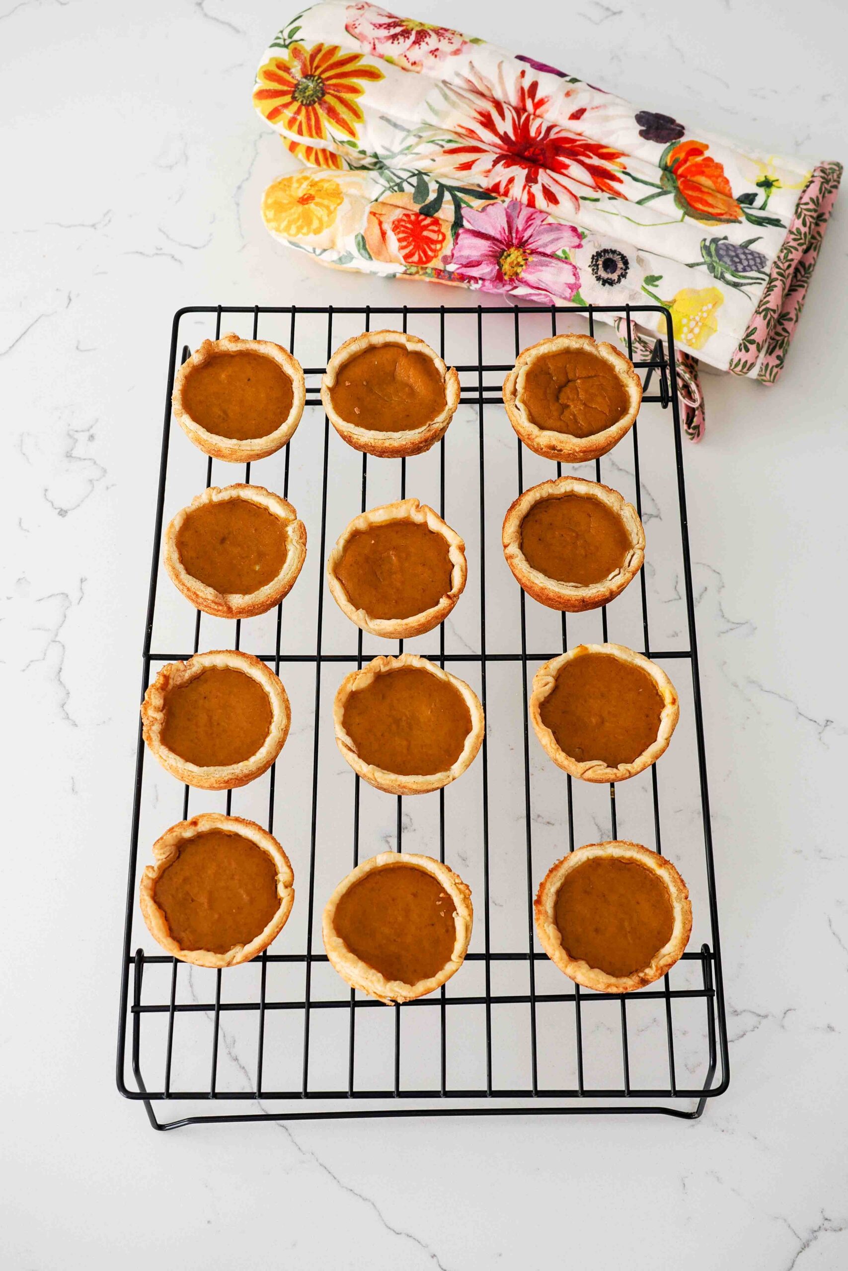 Pumpkin pies made in a muffin pan cooling on a wire rack.