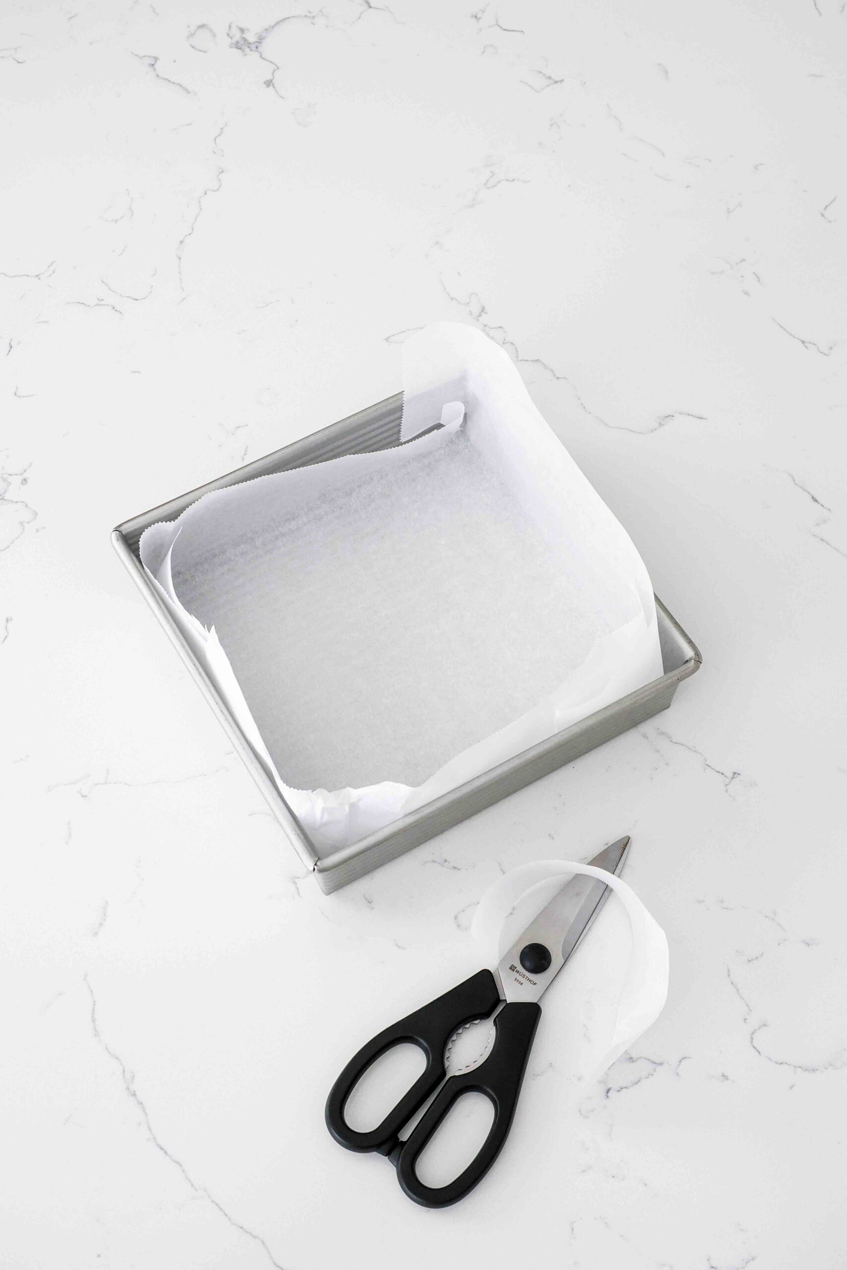 A square pan is lined with parchment paper.