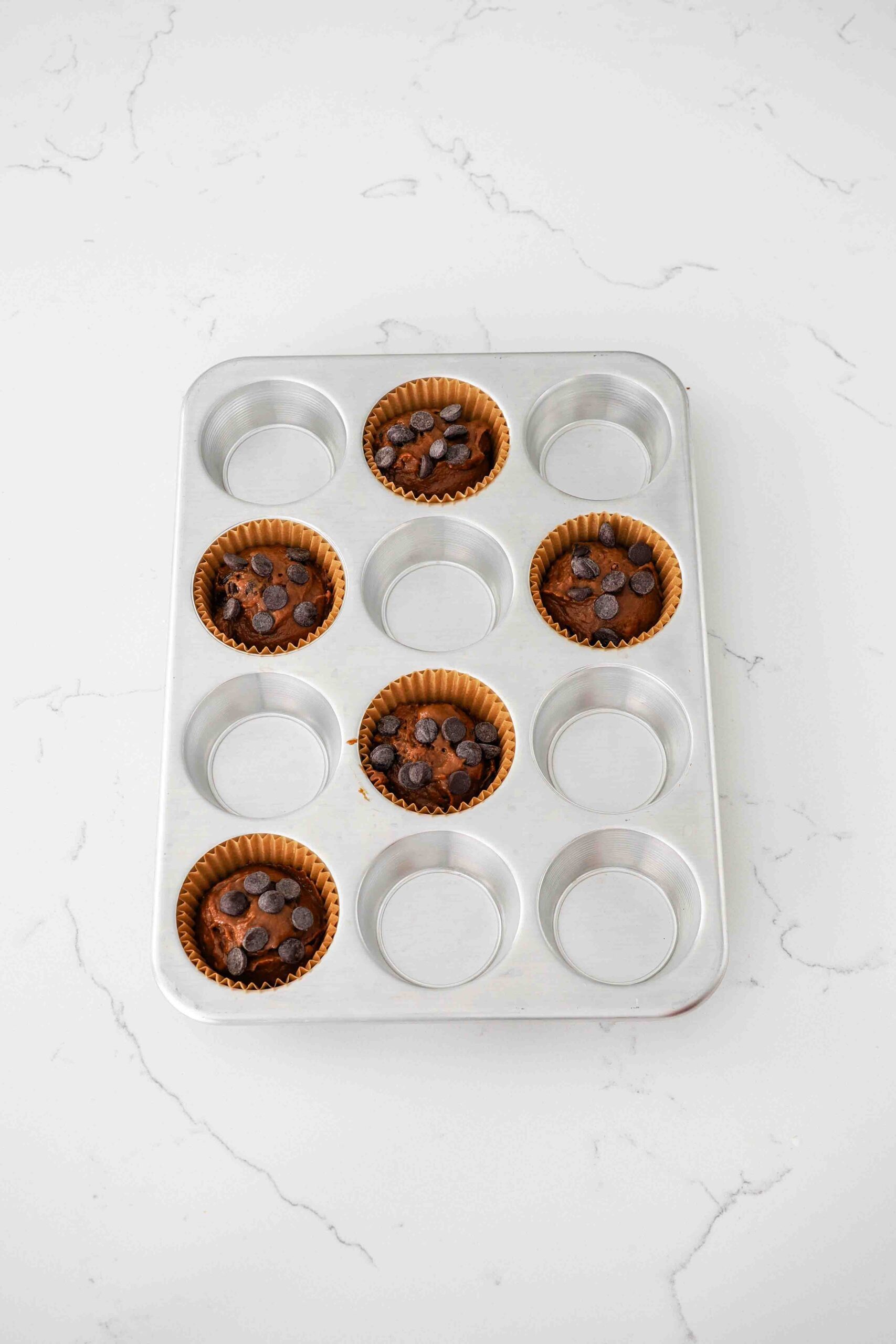 Chocolate pumpkin muffins in paper muffin cups and topped with extra chocolate chips.