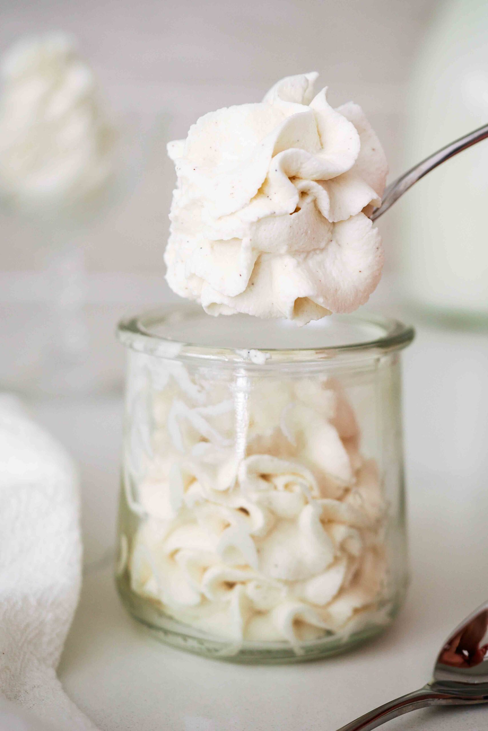 A spoonful of vanilla whipped cream over a full jar.
