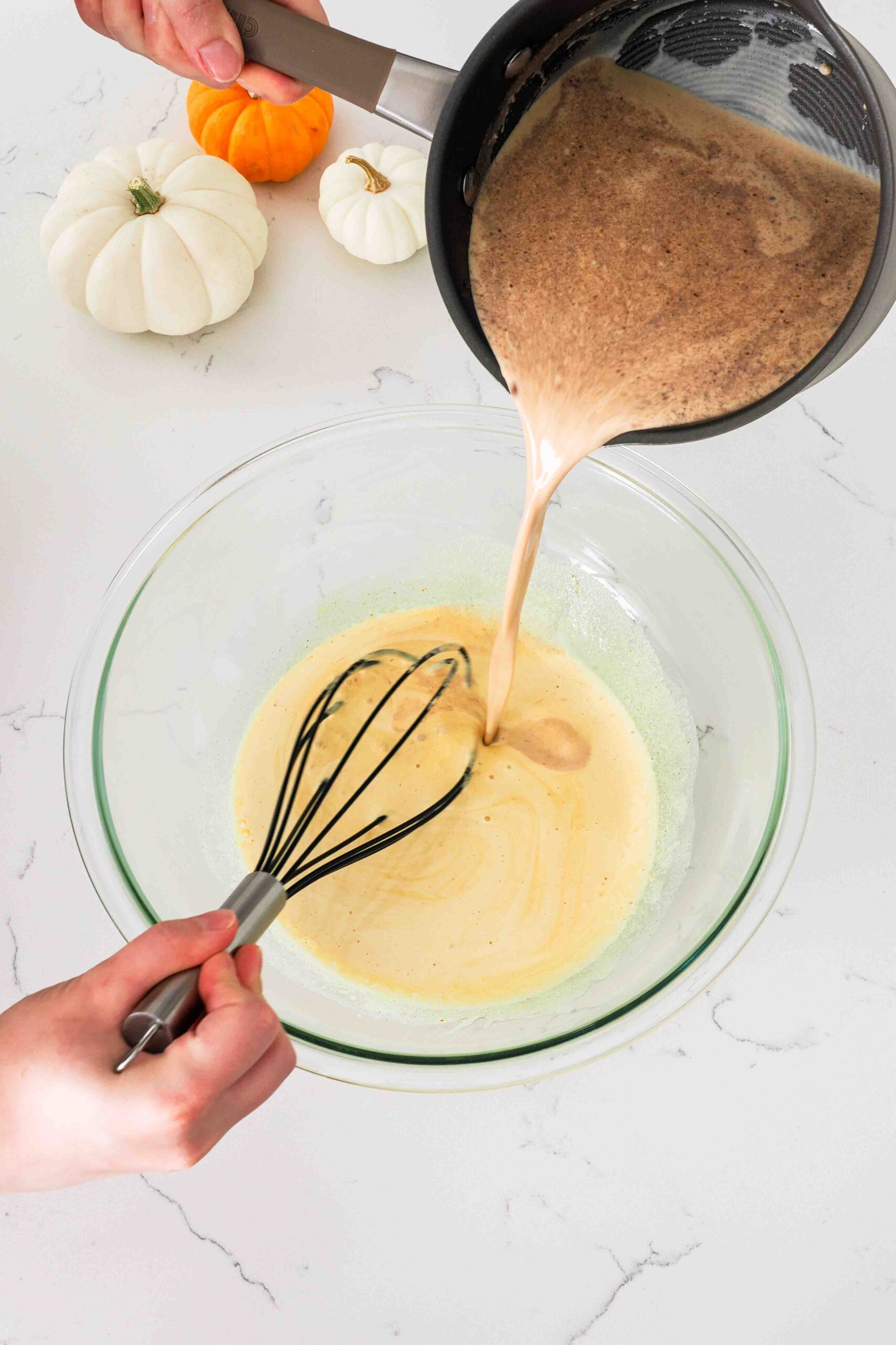Pumpkin cream is poured into a large bowl to temper the egg yolks.