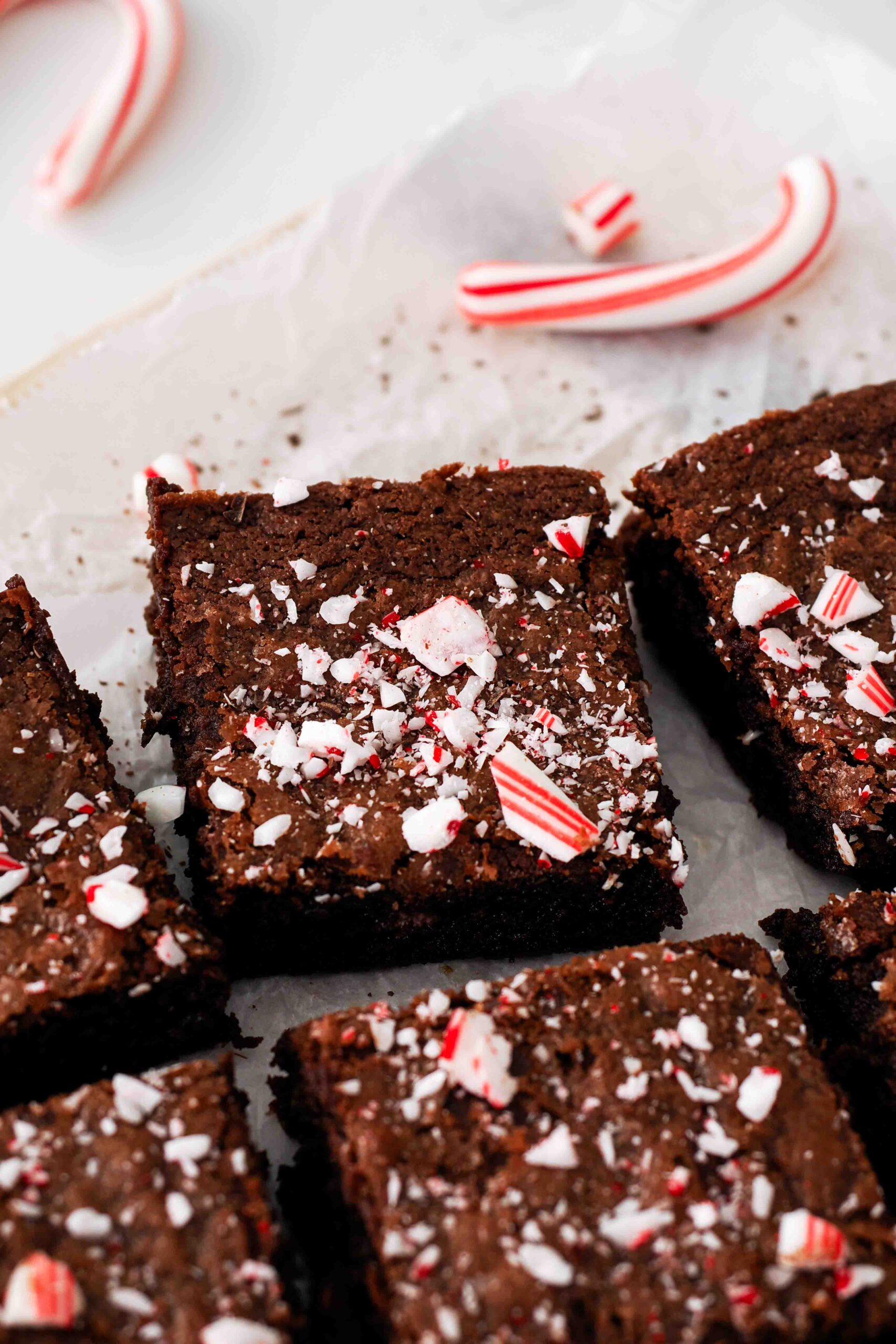 An edge brownie piece on a crumpled sheet of parchment with a candy cane.