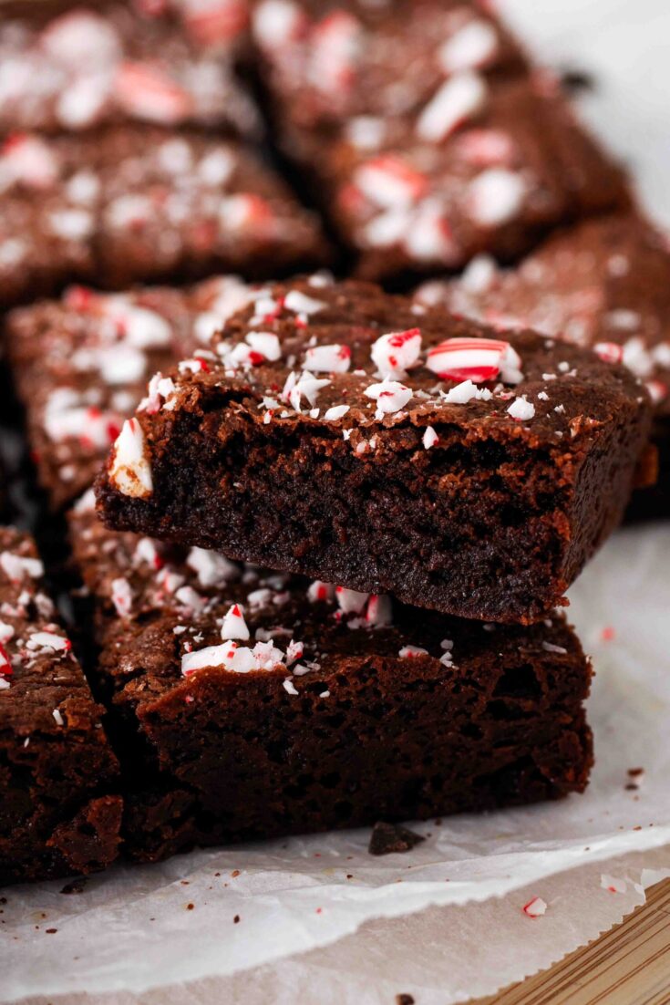 A closeup of a fudgy peppermint brownie with candy cane pieces.