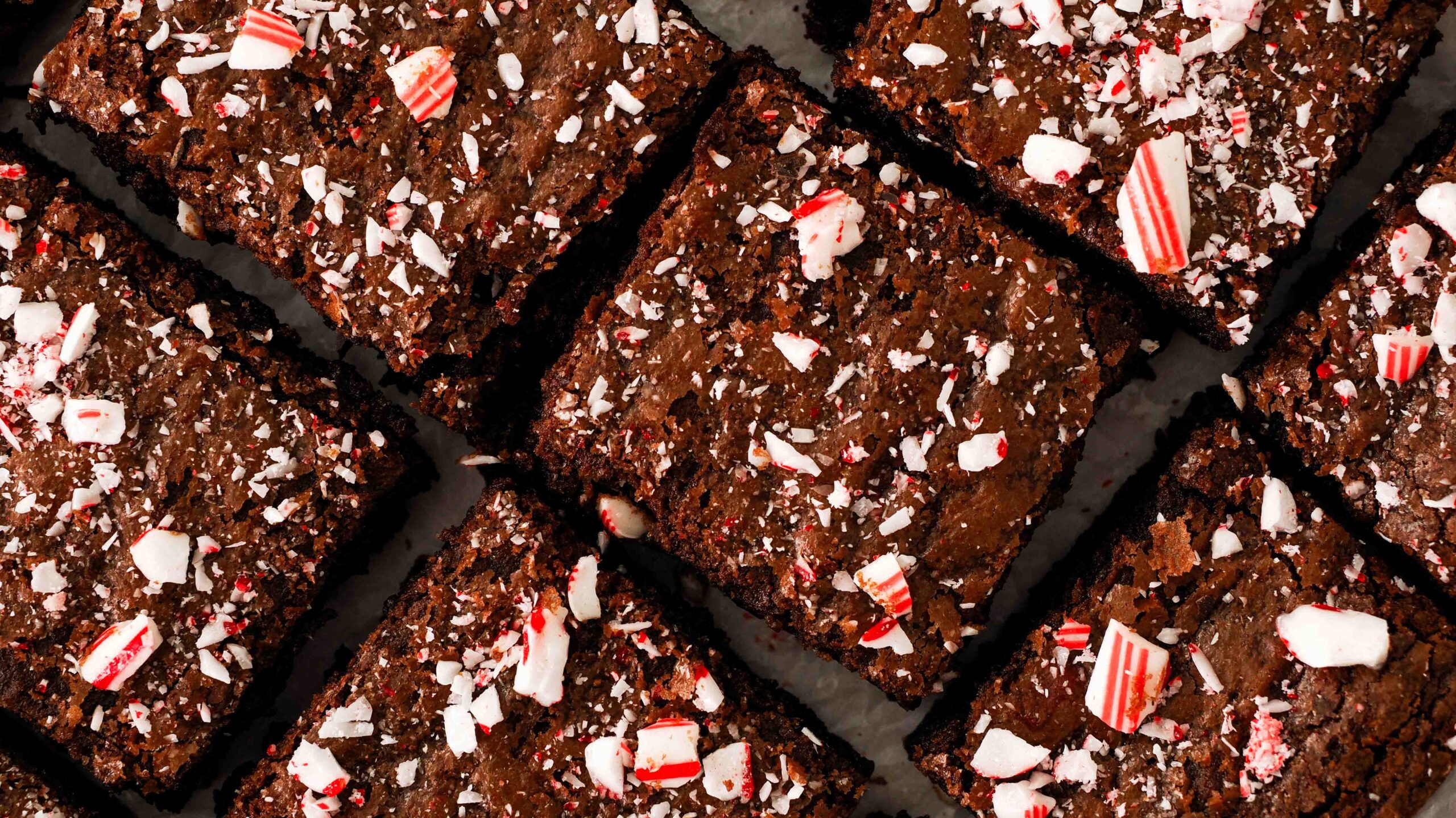 A closeup of peppermint brownie squares on parchment paper.