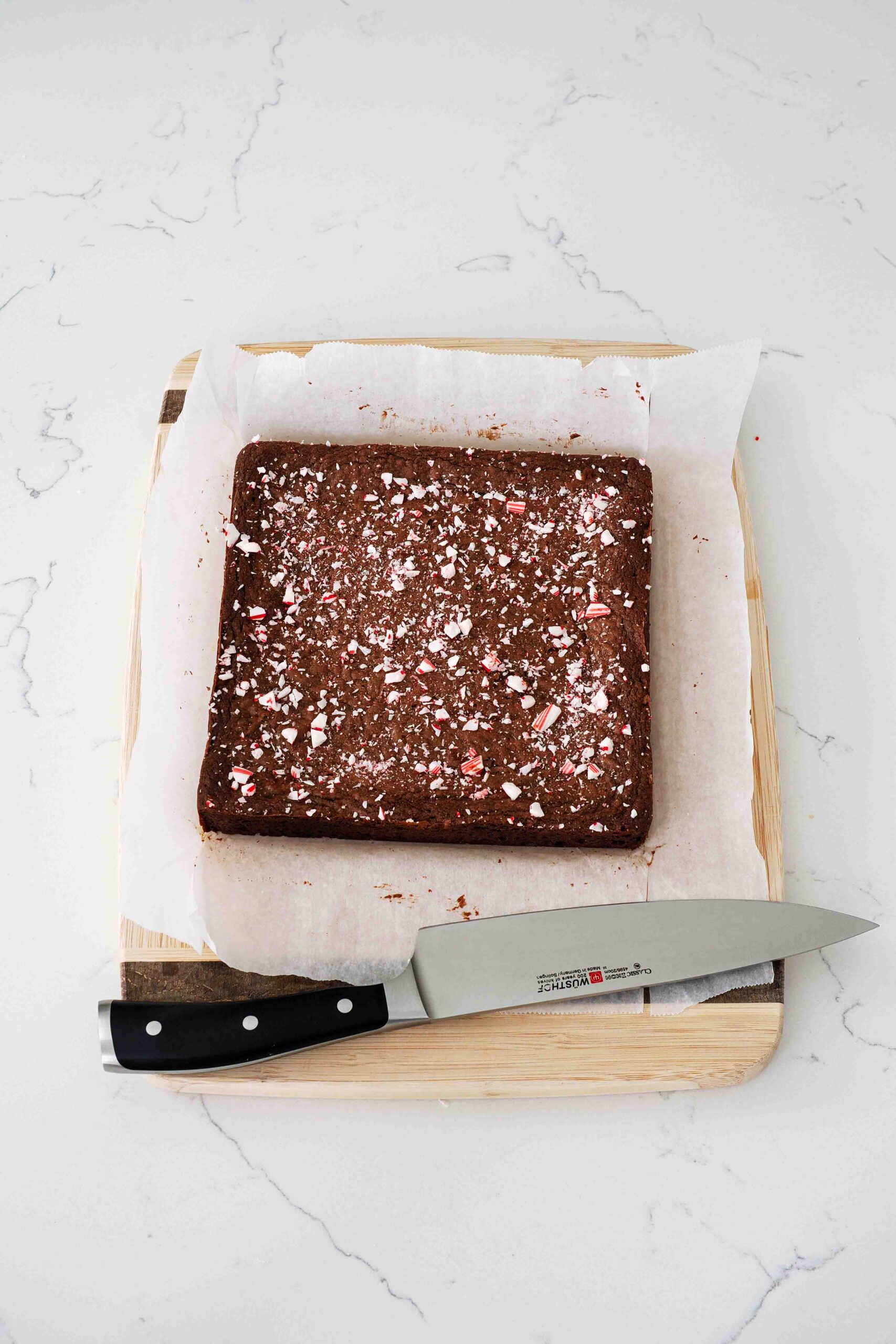 A slab of candy cane brownies cooling on a cutting board.