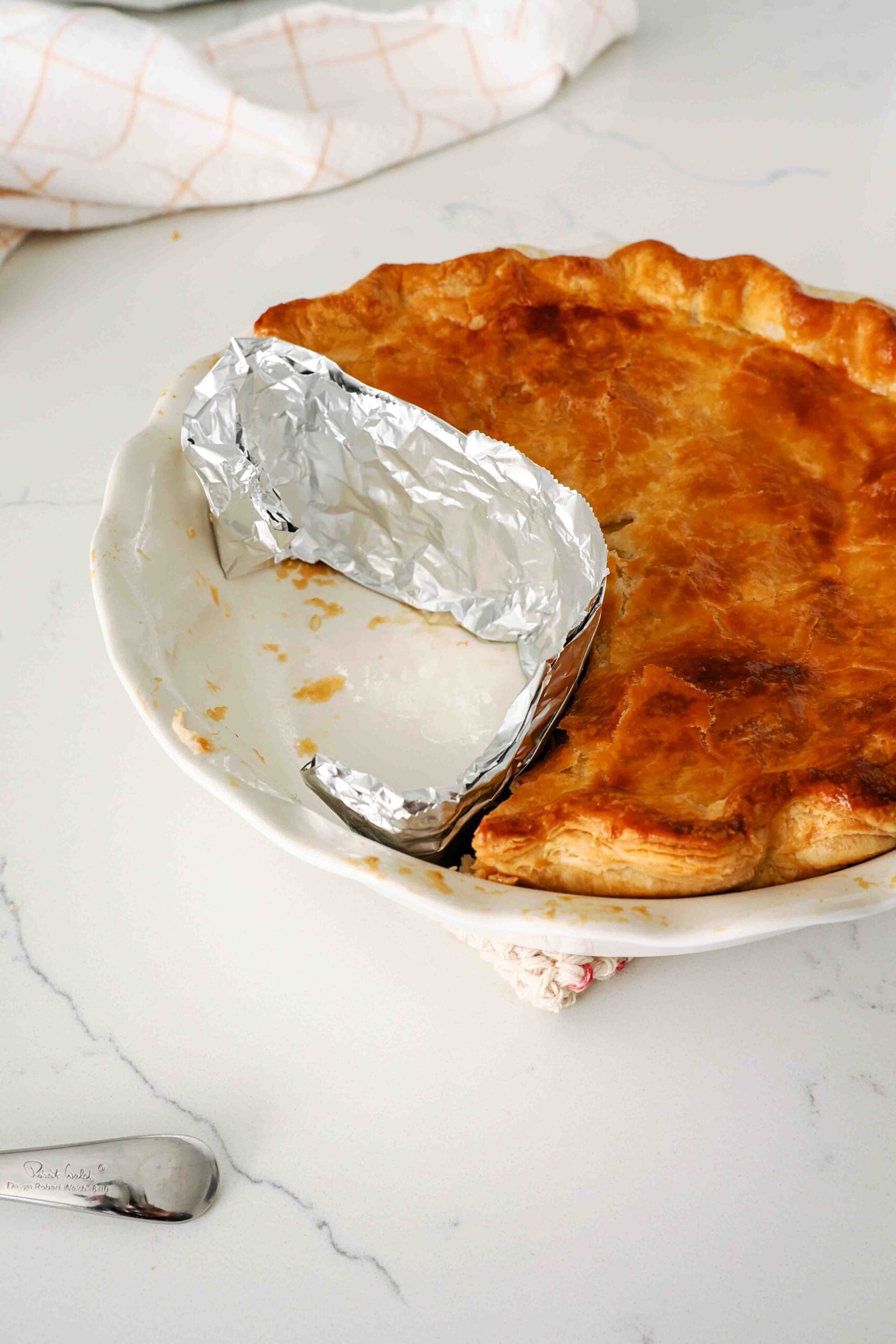 A strip of foil seals off where pieces of chicken pot pie used to be in a pie pan.