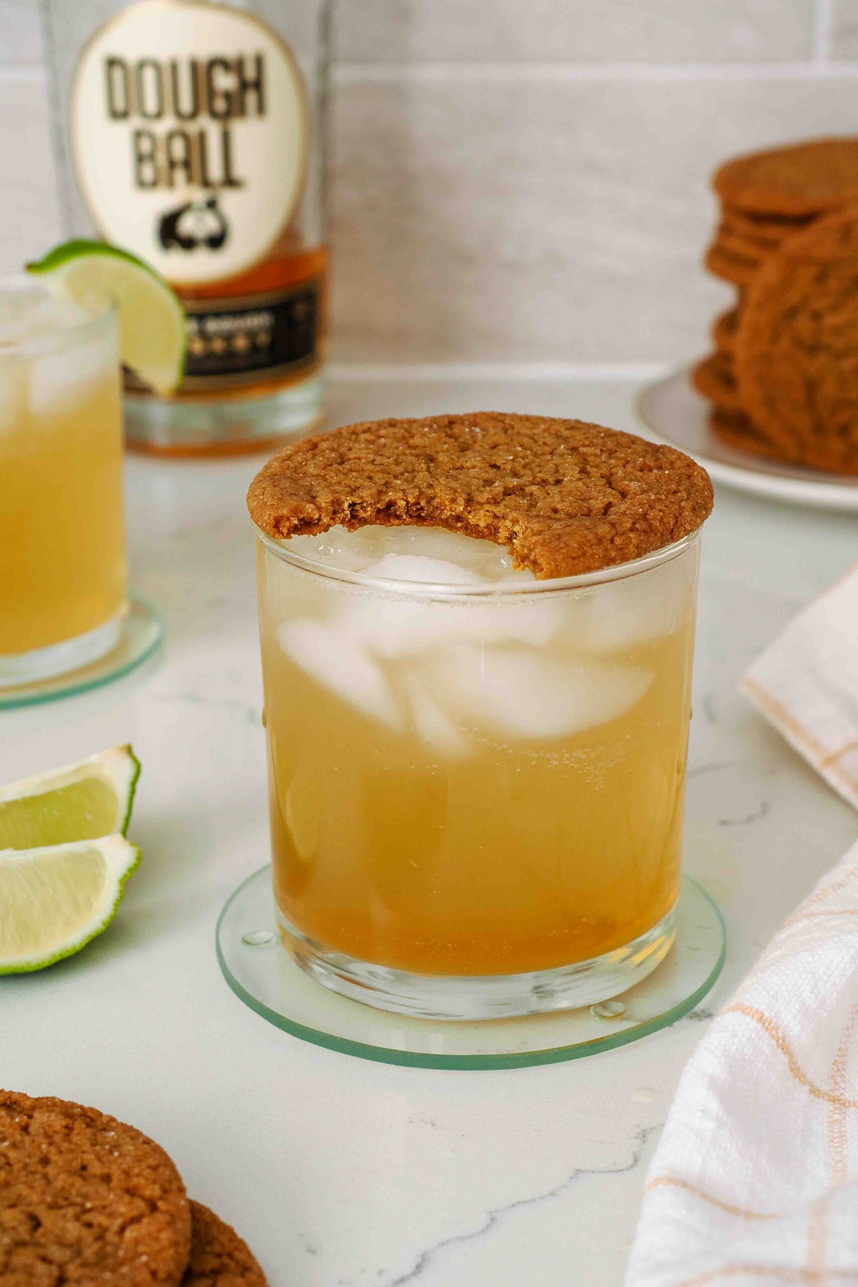 A lowball glass with a whiskey gingersnap cocktail, topped with a gingersnap cookie.