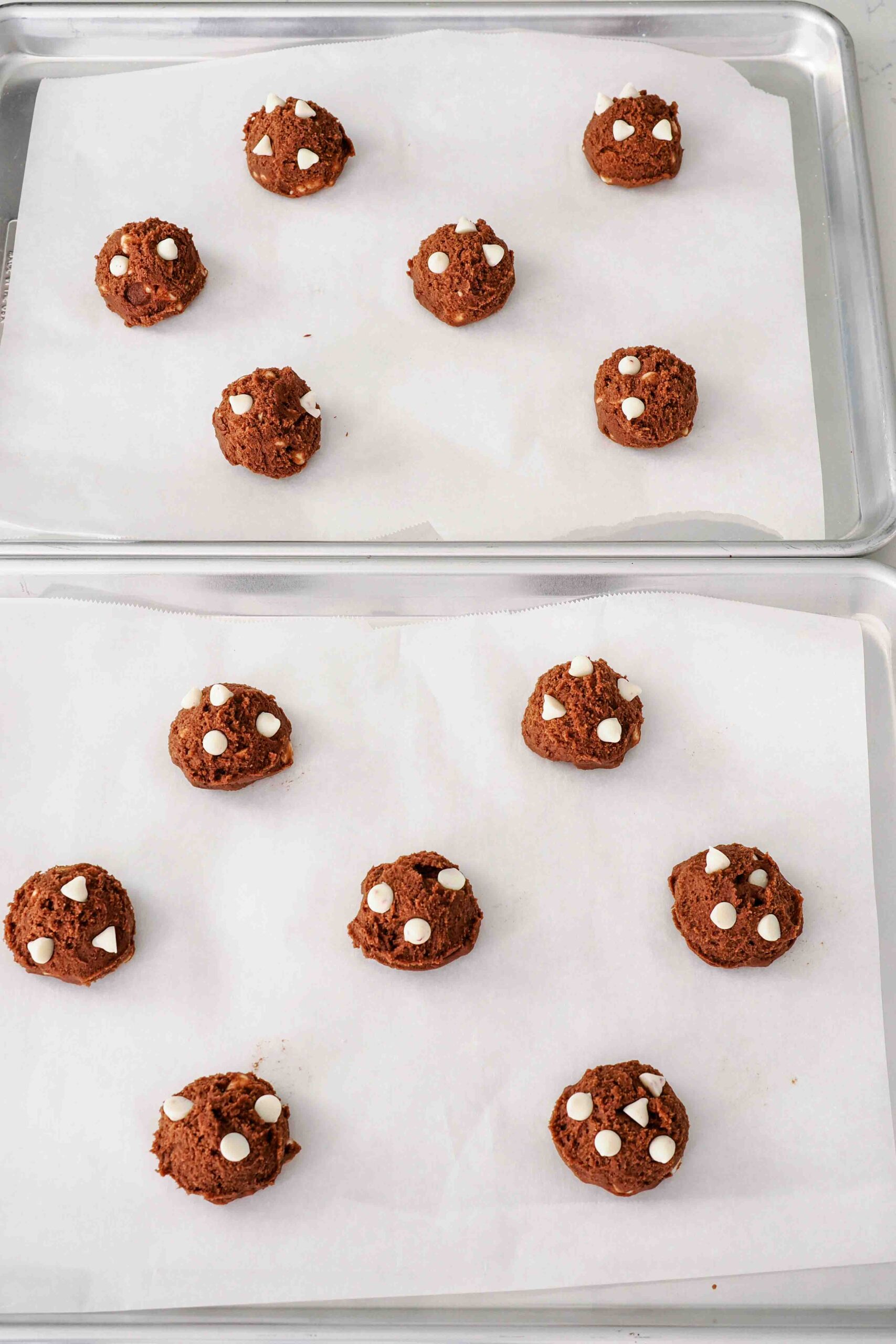 Unbaked chocolate peppermint cookies on parchment-lined baking sheets.