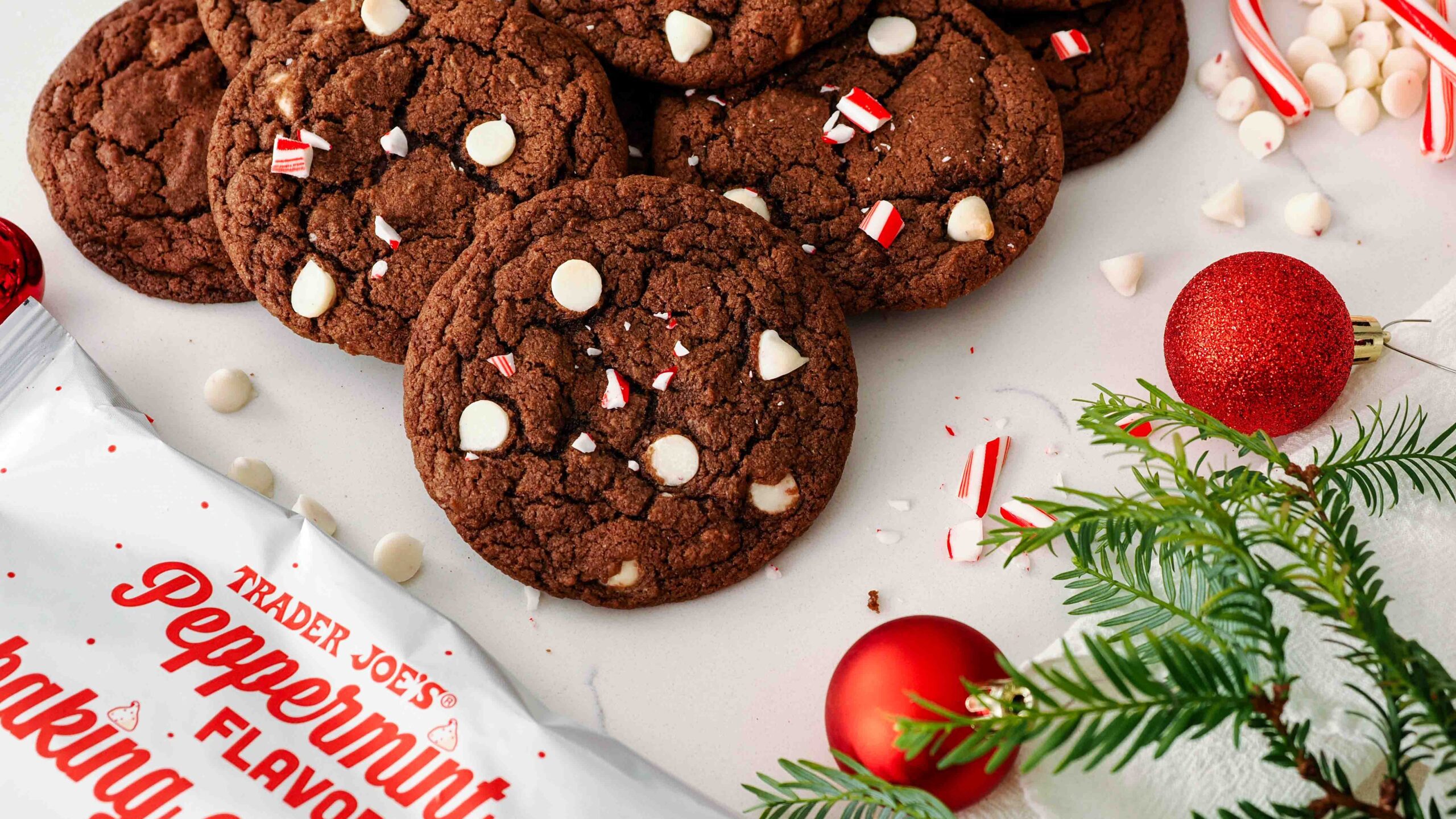 A pile of chocolate peppermint cookies near a bag of peppermint chips.