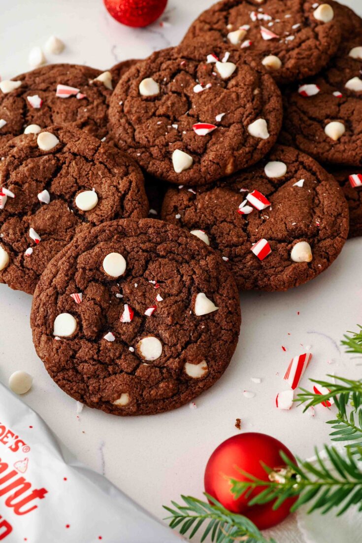 A pile of chocolate peppermint cookies with a red Christmas ornament nearby.