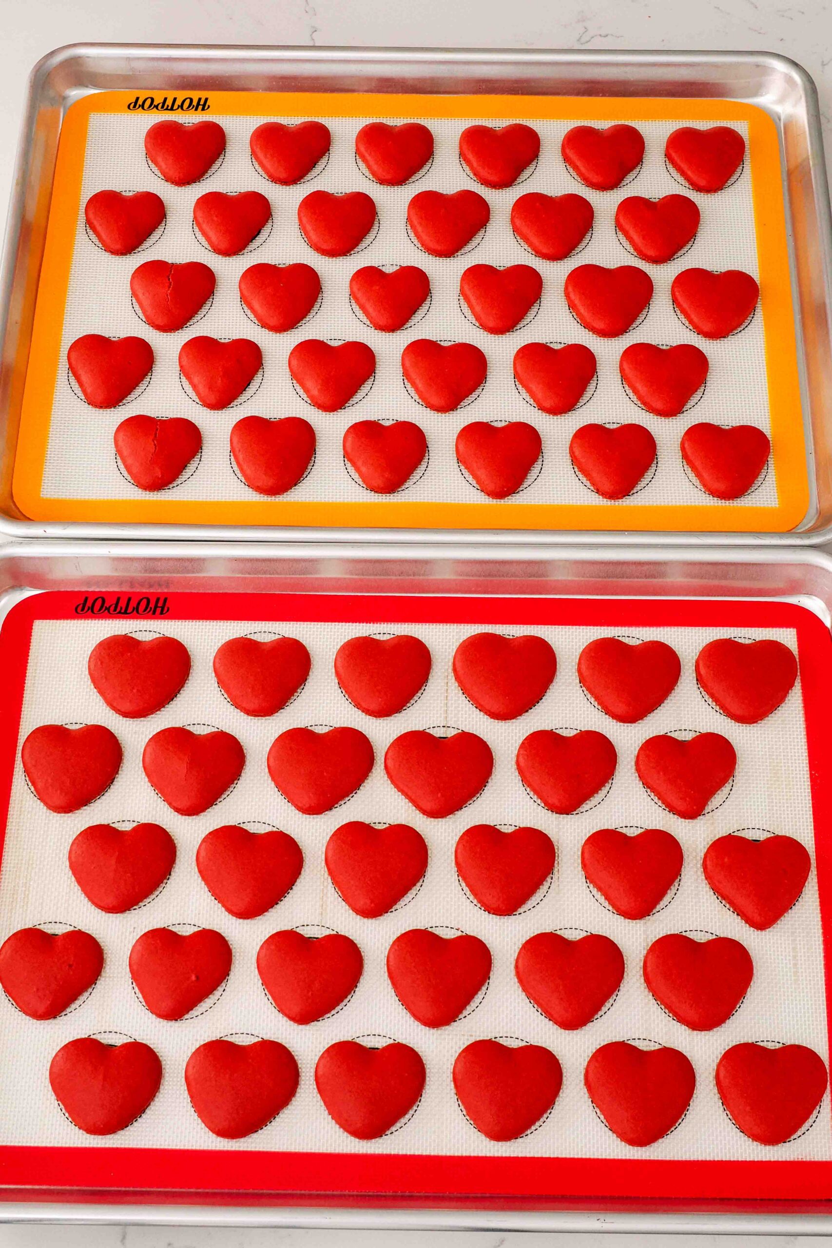 Freshly baked heart macarons on silicone macaron mats.