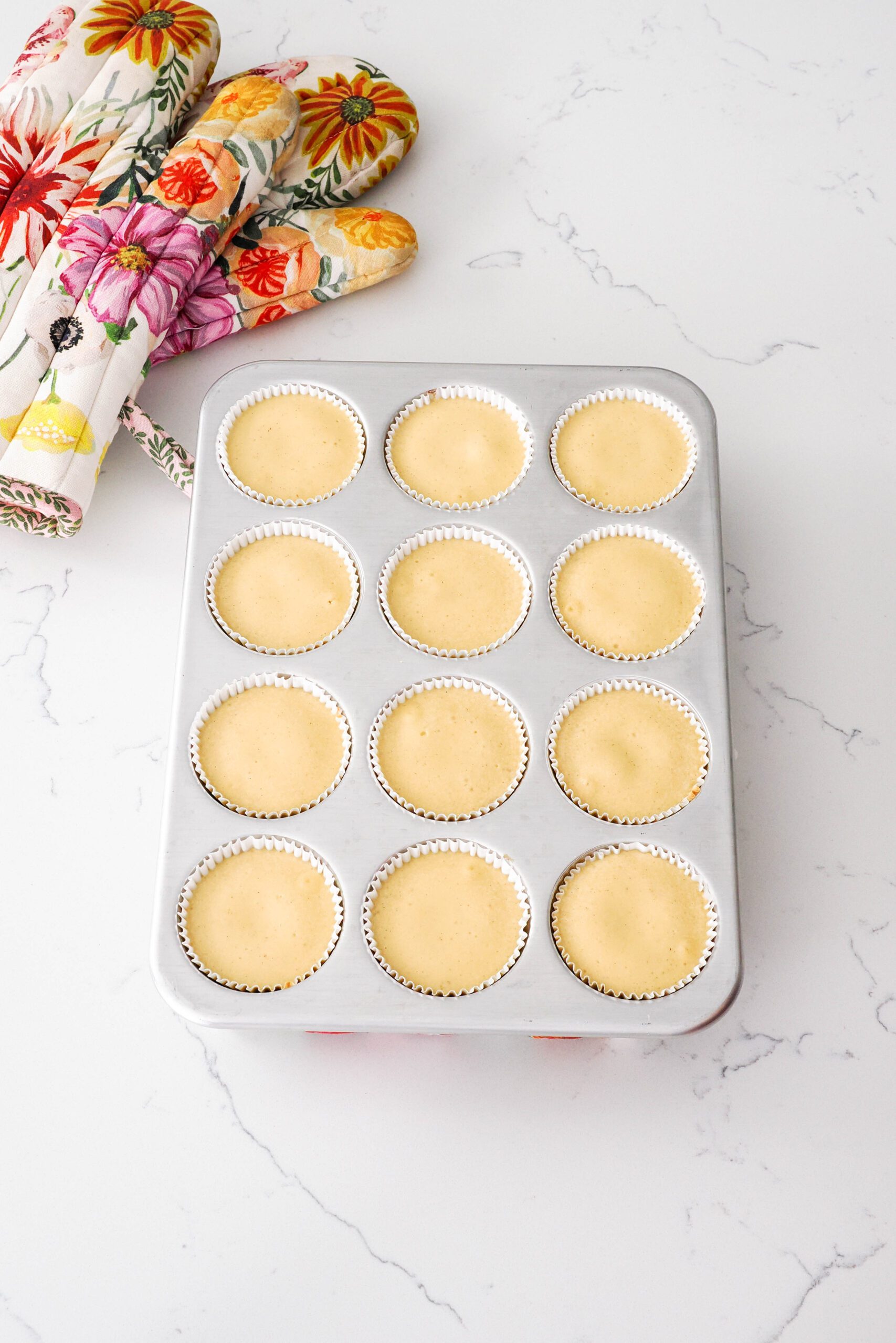 Baked caramel cheesecakes in a muffin pan on a quartz countertop.