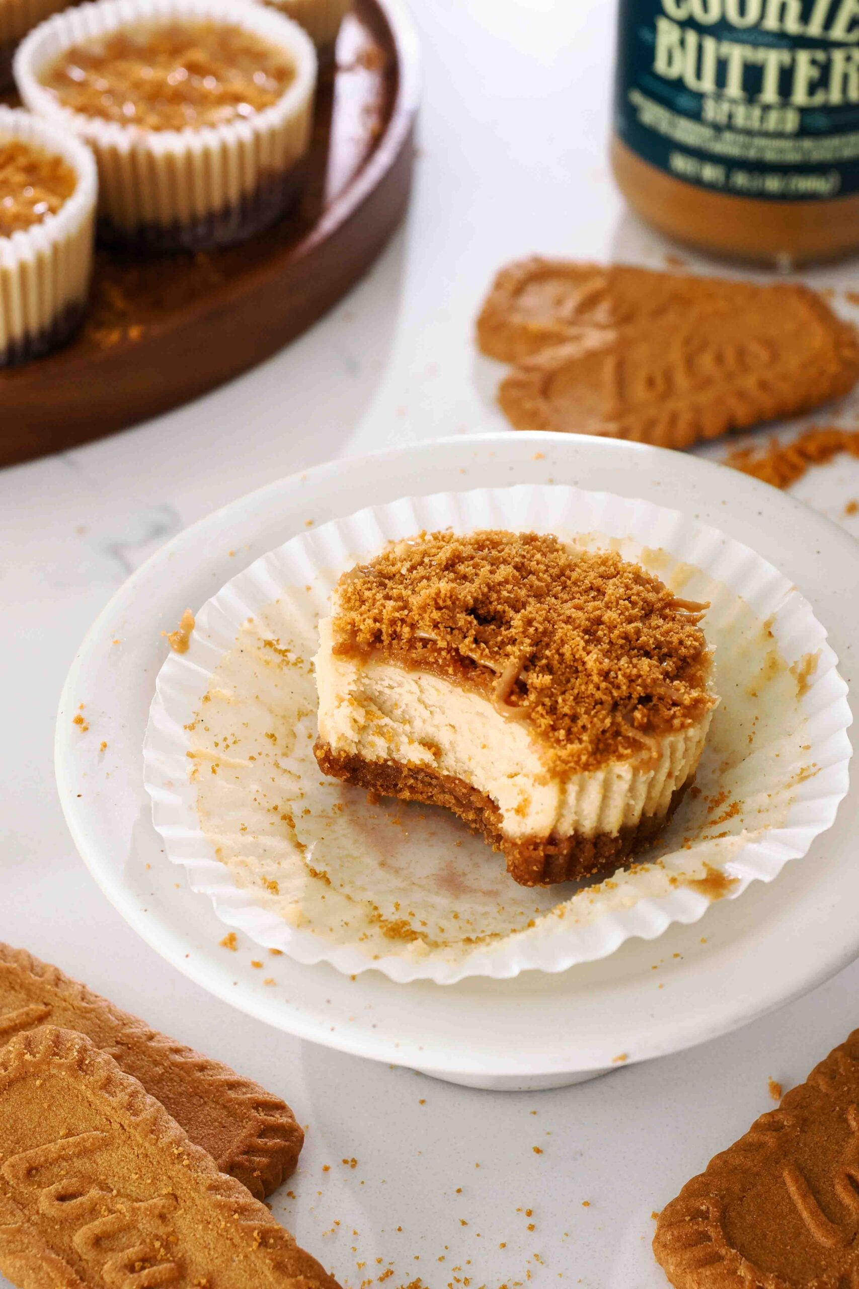 A bite is missing from a mini Biscoff cheesecake on a small platter.