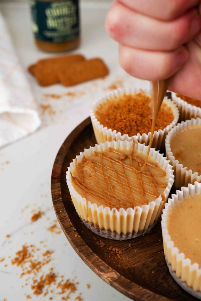 Warm cookie butter is drizzled on top of a mini Biscoff cheesecake.
