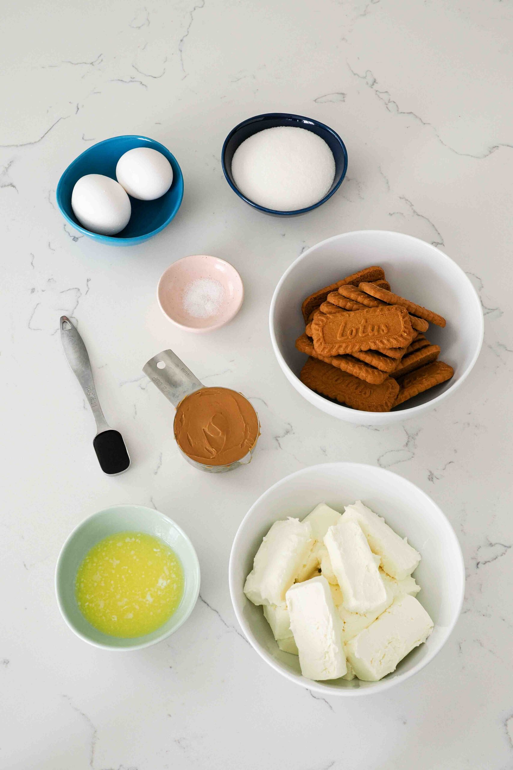 Ingredients for mini Biscoff cheesecakes on a quartz countertop.