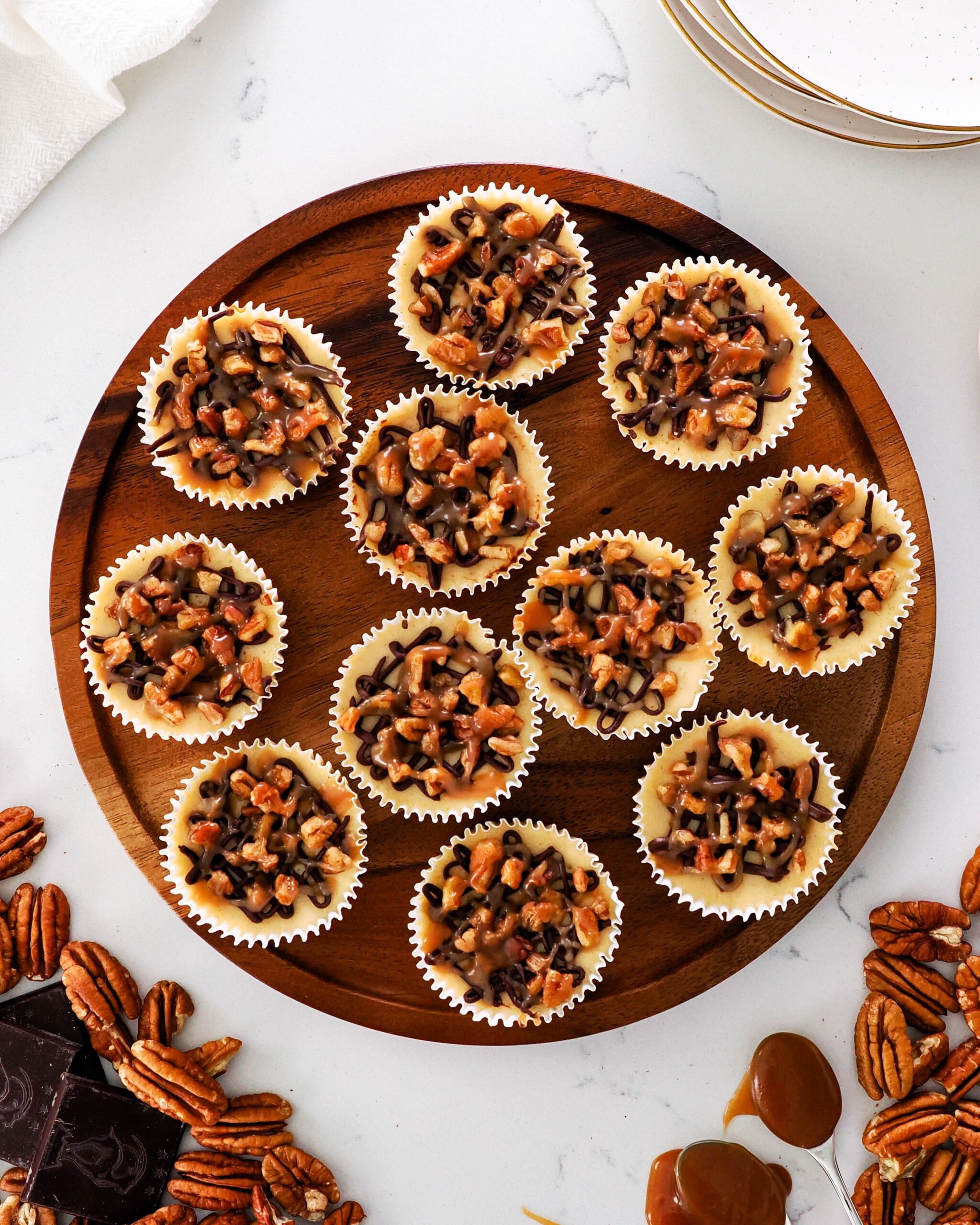 An overhead view of mini turtle cheesecakes on a wooden platter.