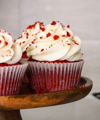 Red velvet cupcakes on a wooden cake stand.
