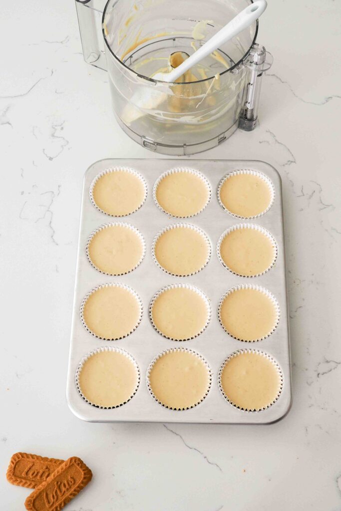 Unbaked Biscoff cheesecakes in a muffin pan.