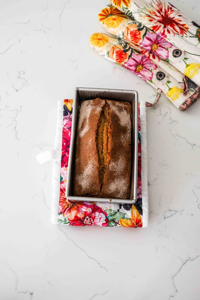 Fully baked cinnamon banana bread on a hot pad on a counter.