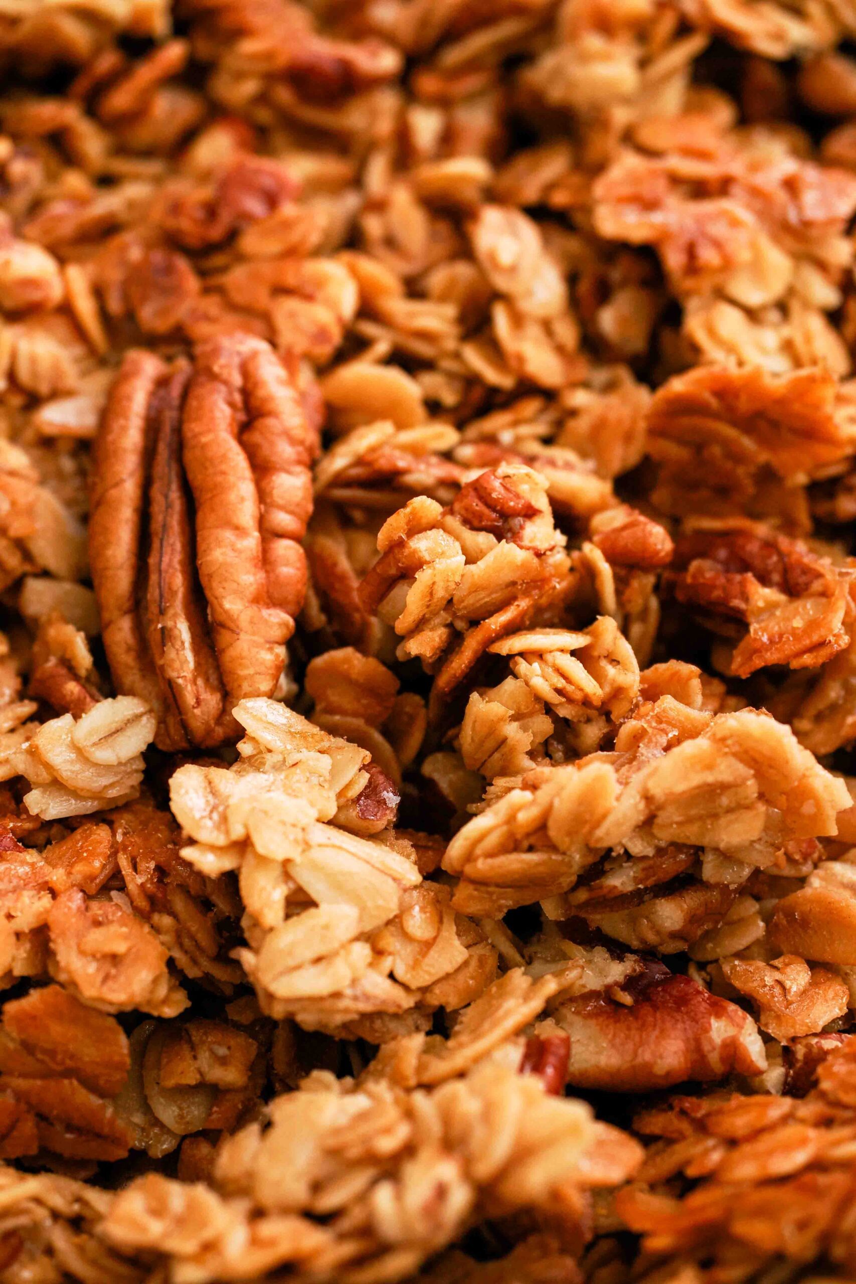 A closeup of honey pecan granola clusters with pieces of pecan.