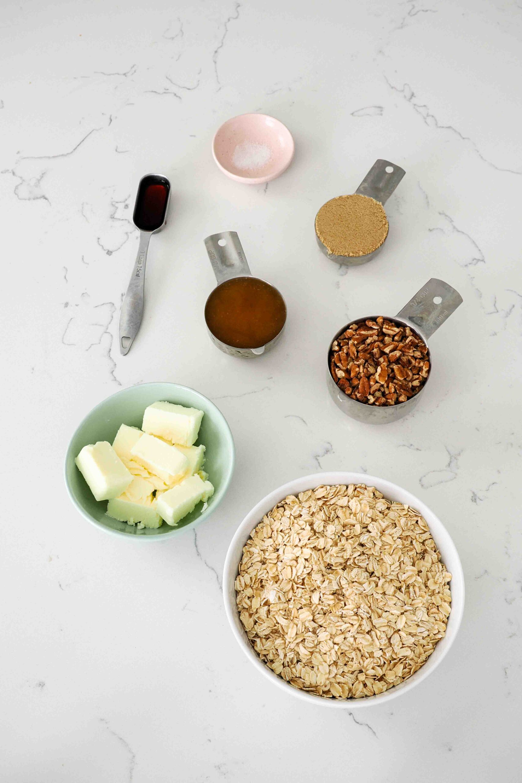 Ingredients for honey pecan granola on a quartz kitchen counter.