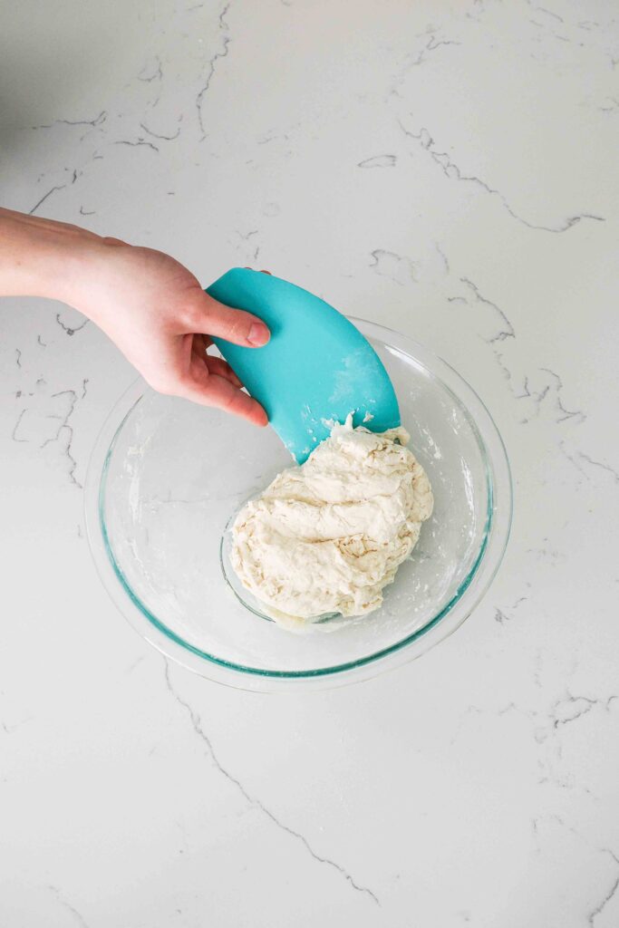 Shaggy focaccia dough in a glass mixing bowl.
