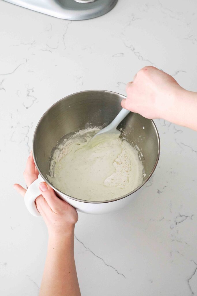 A spatula folds flour, baking powder, and salt into whipped eggs with lavender sugar.