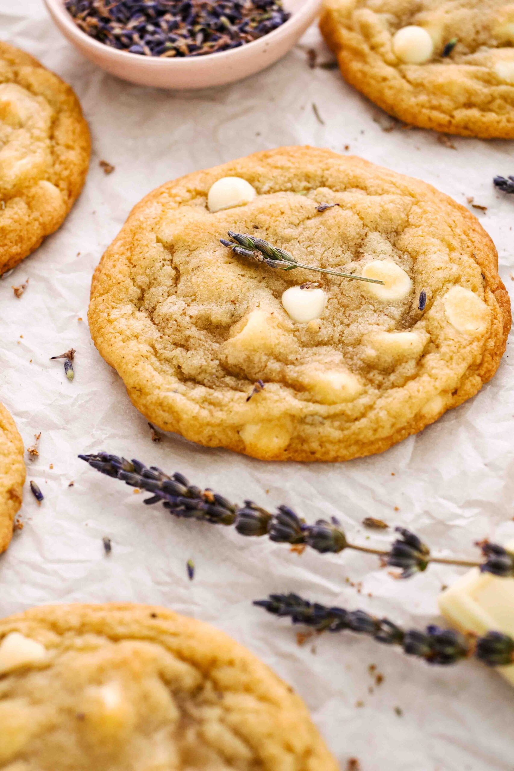 A small sprig of lavender rests on top of a lavender white chocolate chip cookie.