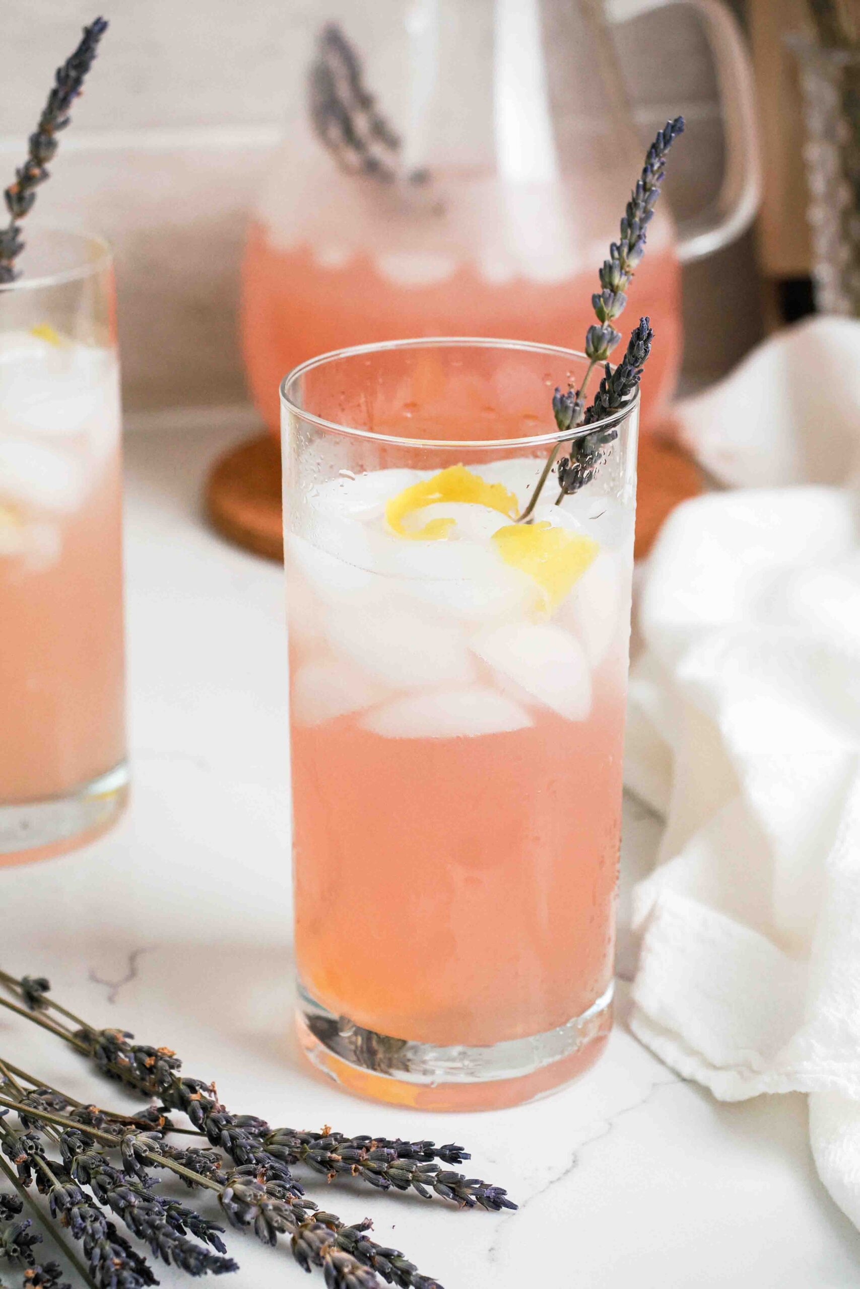 Pink lavender lemonade in a tall glass with a sprig of lavender.
