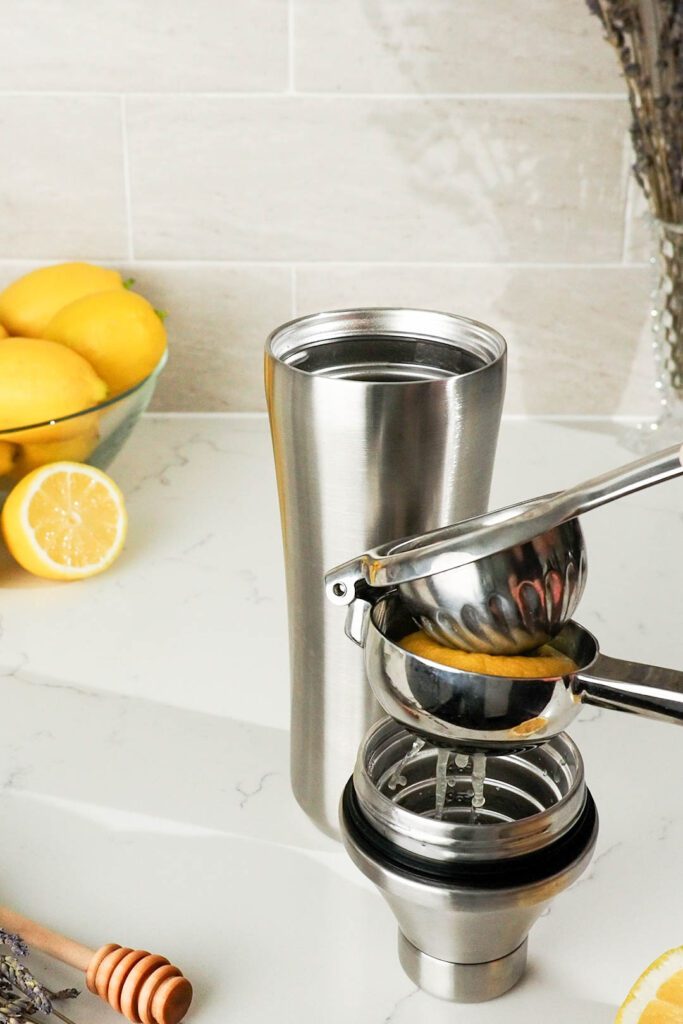 Juice is squeezed from a lemon into a jigger.