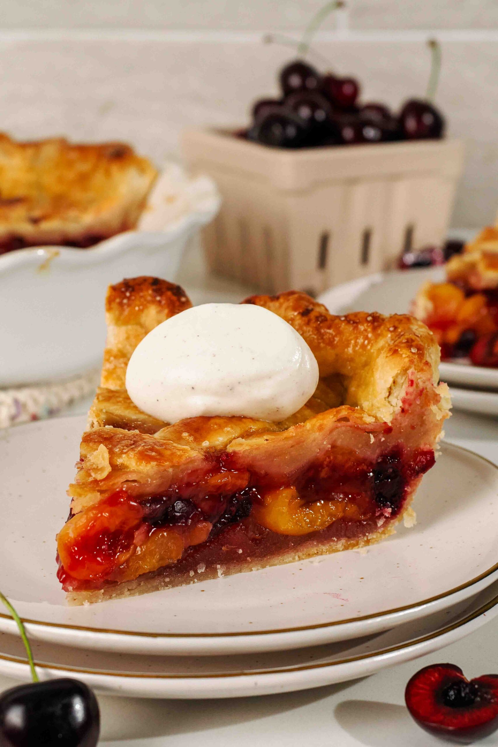 A slice of cherry pie with vanilla whipped cream on top.