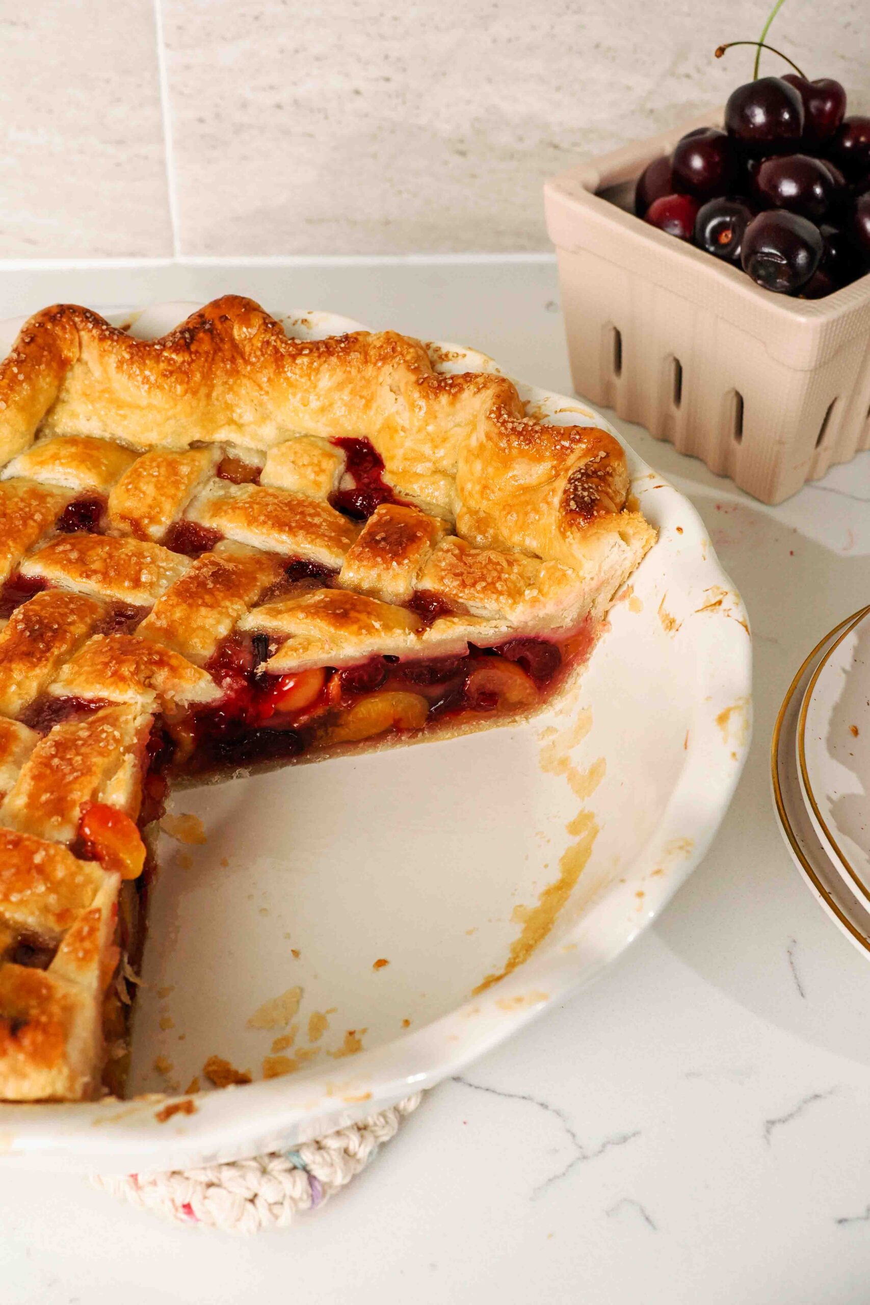 A quarter of a cherry pie is missing from a pie pan.