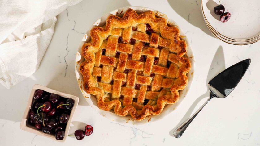 An overhead image of a golden brown cherry lattice pie with almond extract.