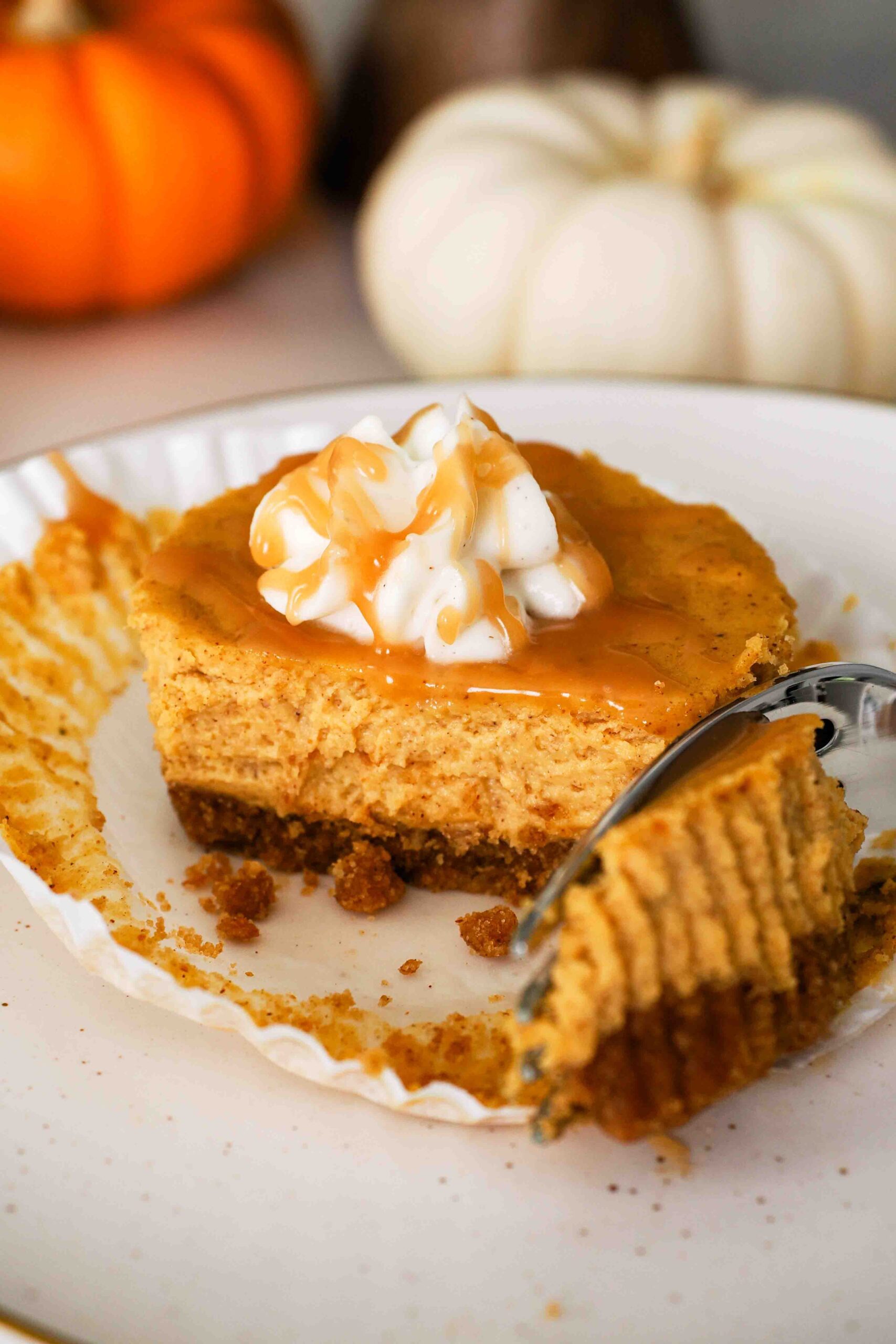 A fork removes a piece of a mini pumpkin cheesecake on a plate.