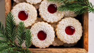 Linzer cookies in a wooden box with pine tree branches.