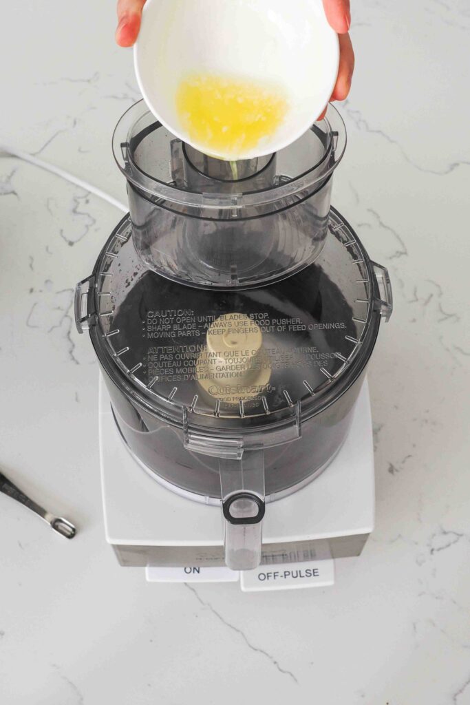 Melted butter is added to a food processor with crushed Oreos.