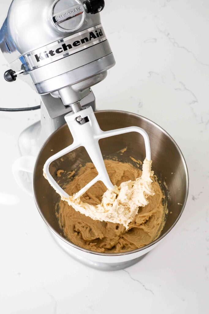 A mixing bowl with creamed butter, sugar, egg, and vanilla for cookie dough.
