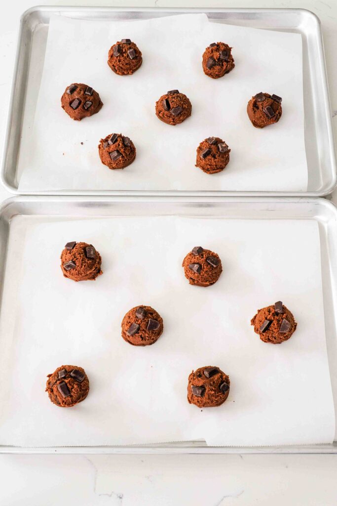 Unbaked double chocolate chip cookie dough balls on a baking sheet.